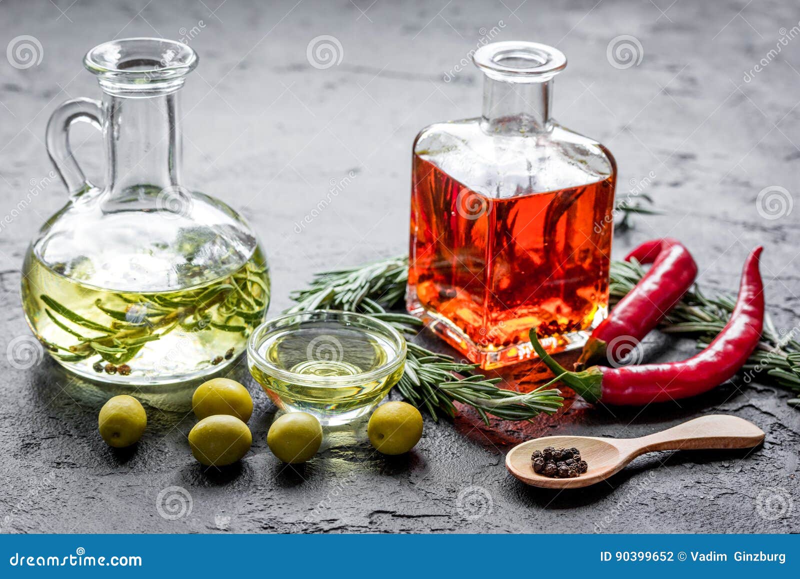 Bottles with Chili and Olive Oils and Herbs on Stone Background Stock