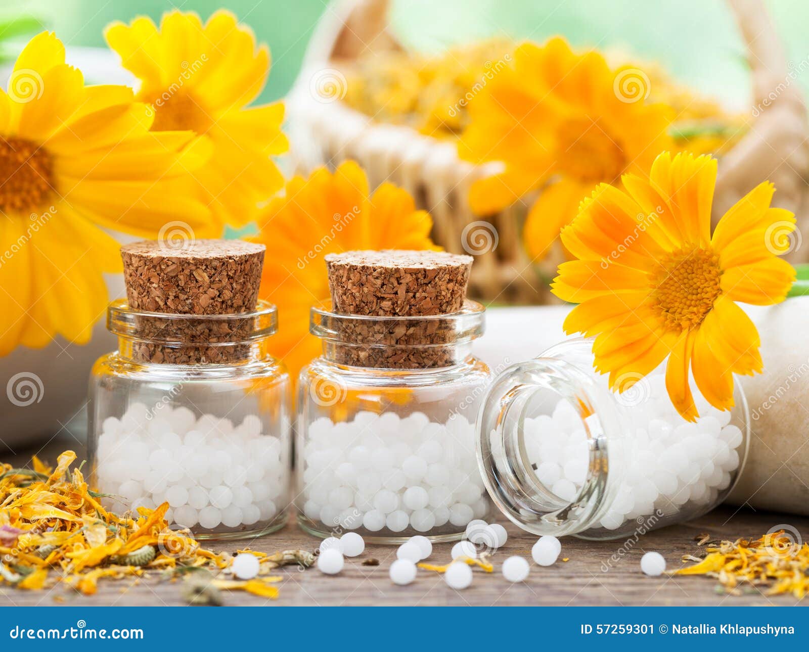 bottles of homeopathy globules and marigold flowers.