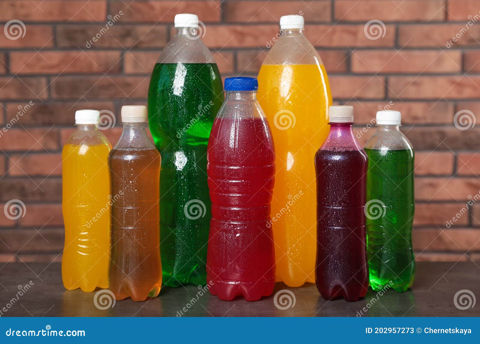 Bottles of Soft Drinks with Water Drops on Table Near Brick Wall Stock