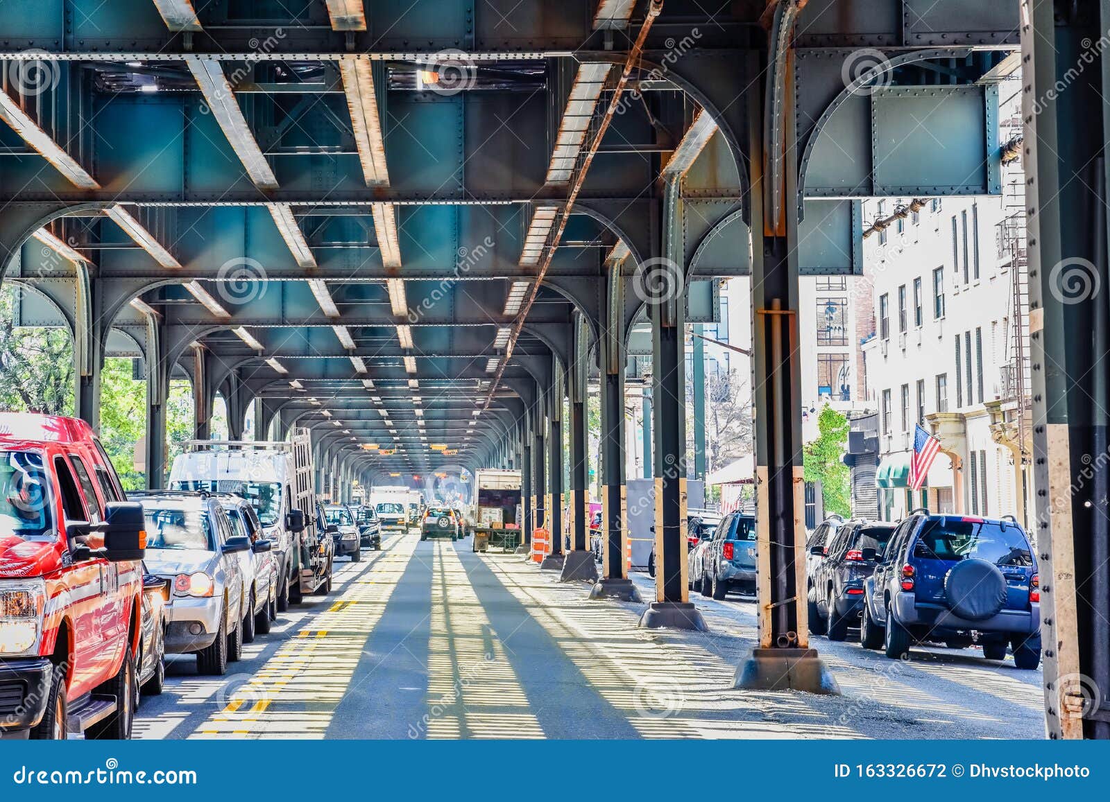 bottom view of elevated train track nyc. traffic waiting in road in a sunny day. travel and traffic . bronx, nyc, usa