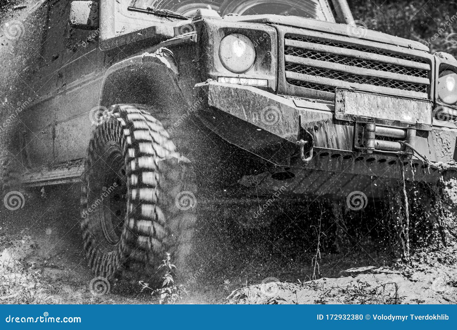 bottom view offroad car wheel on country road and mountains backdrop. off road vehicle coming out of a mud hole hazard.