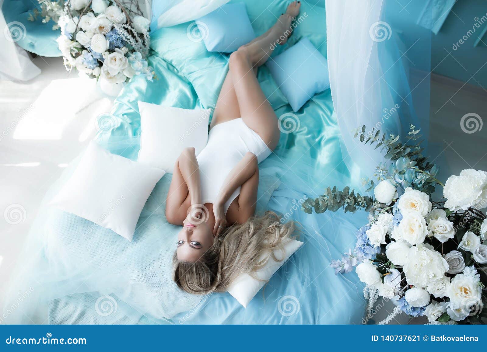 Boudoir Photography. Woman Blonde with Long Hair in Lingerie on the Bed