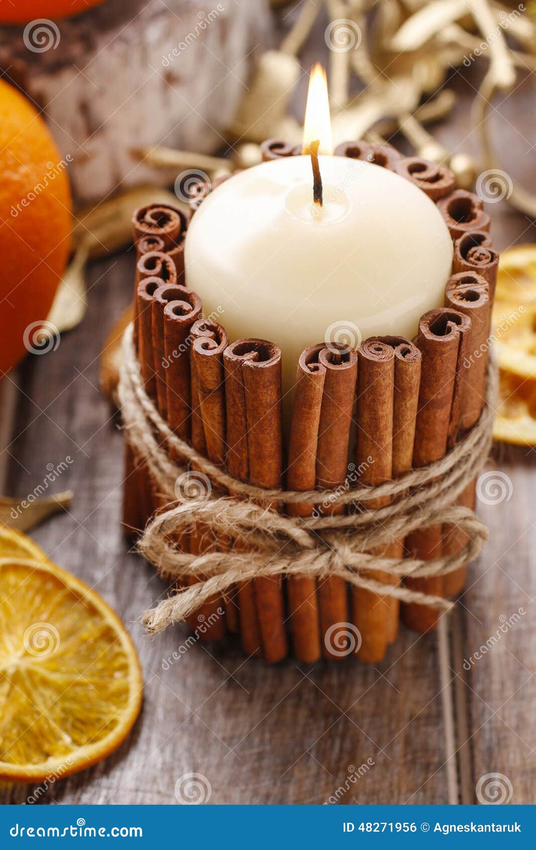 bougie décorée de bâtons de cannelle et de pommes rouges