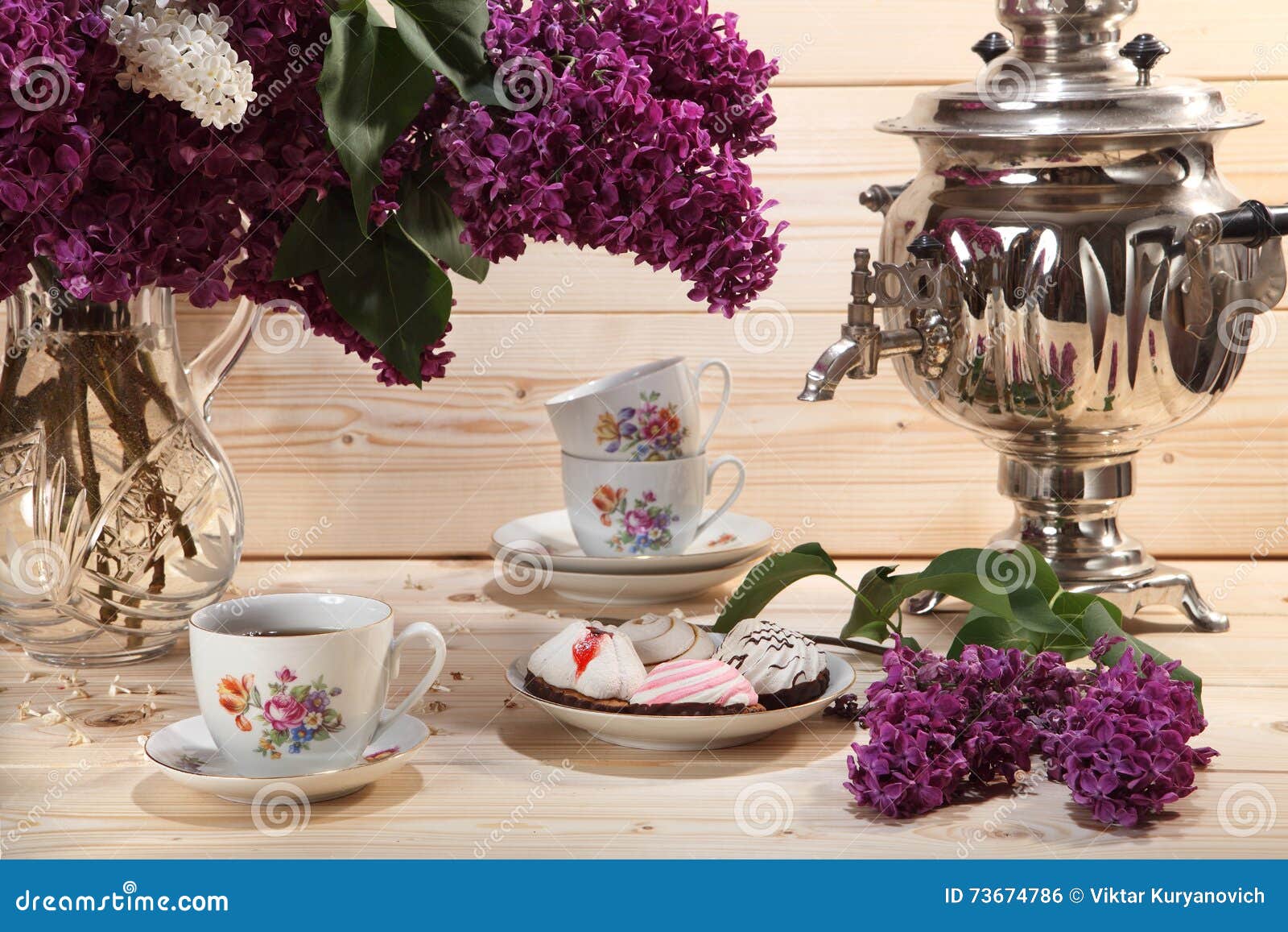 bouquet of lilacs, samovar, cup of tea and buscuit on wooden background