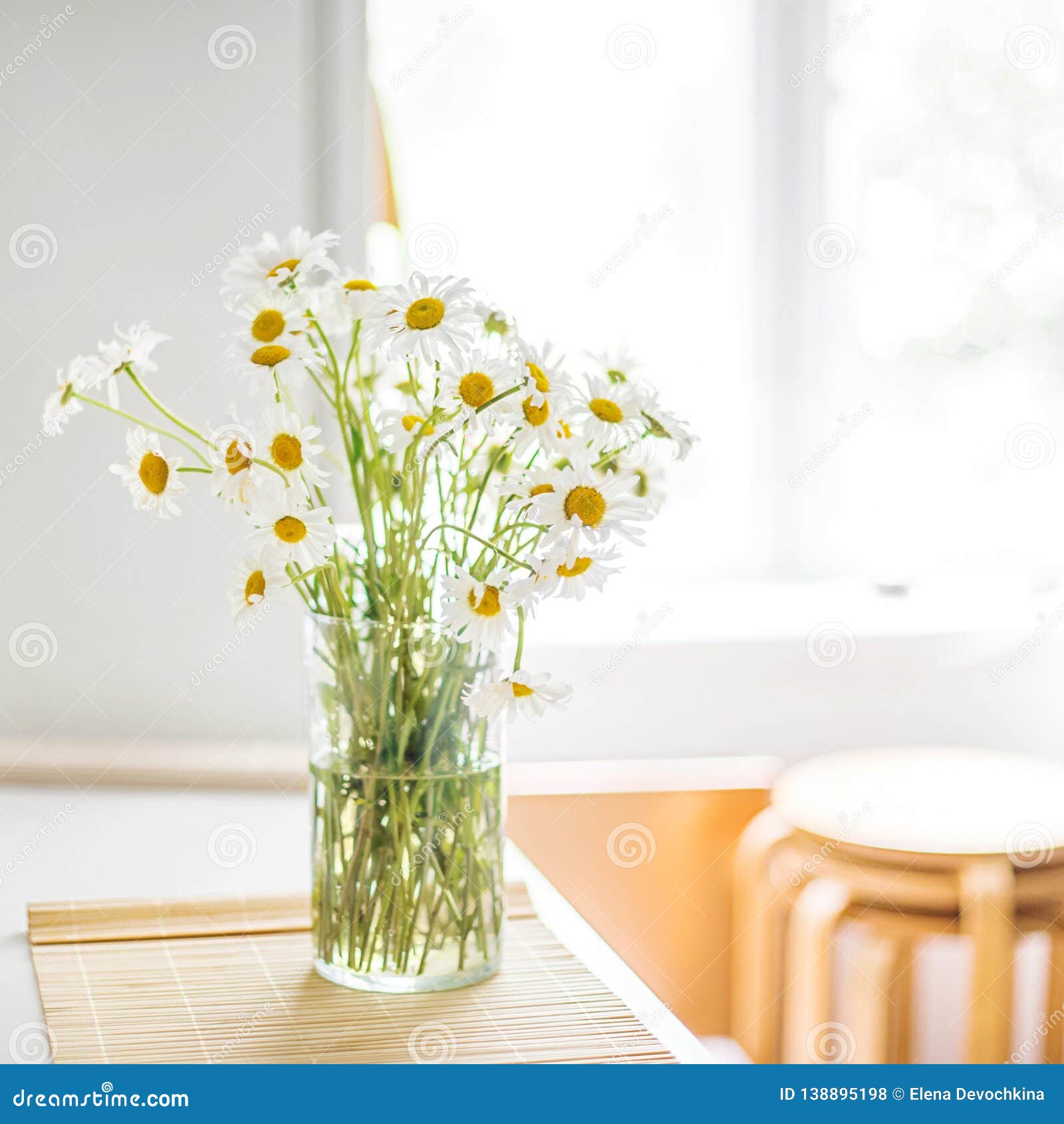 A Bouquet of White Daisies in a Vase on the Kitchen Table Against the