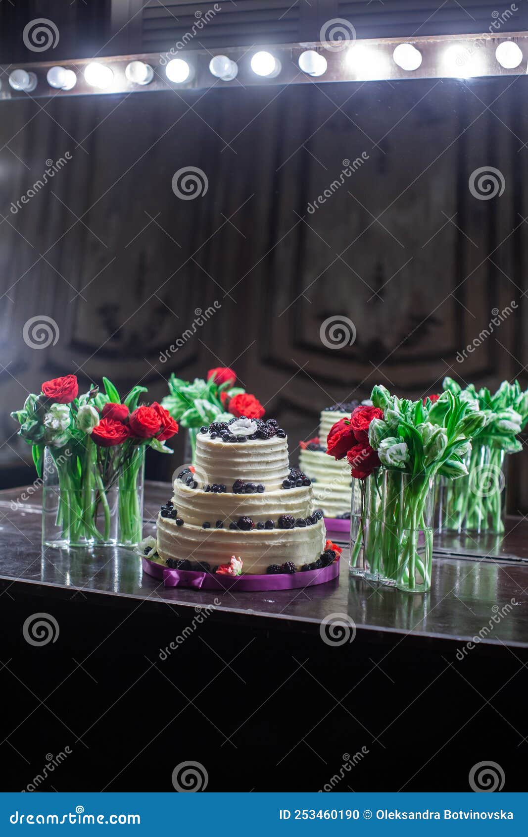Bouquets in Vases and a Wedding Cake Decorated with Berries Stock Photo