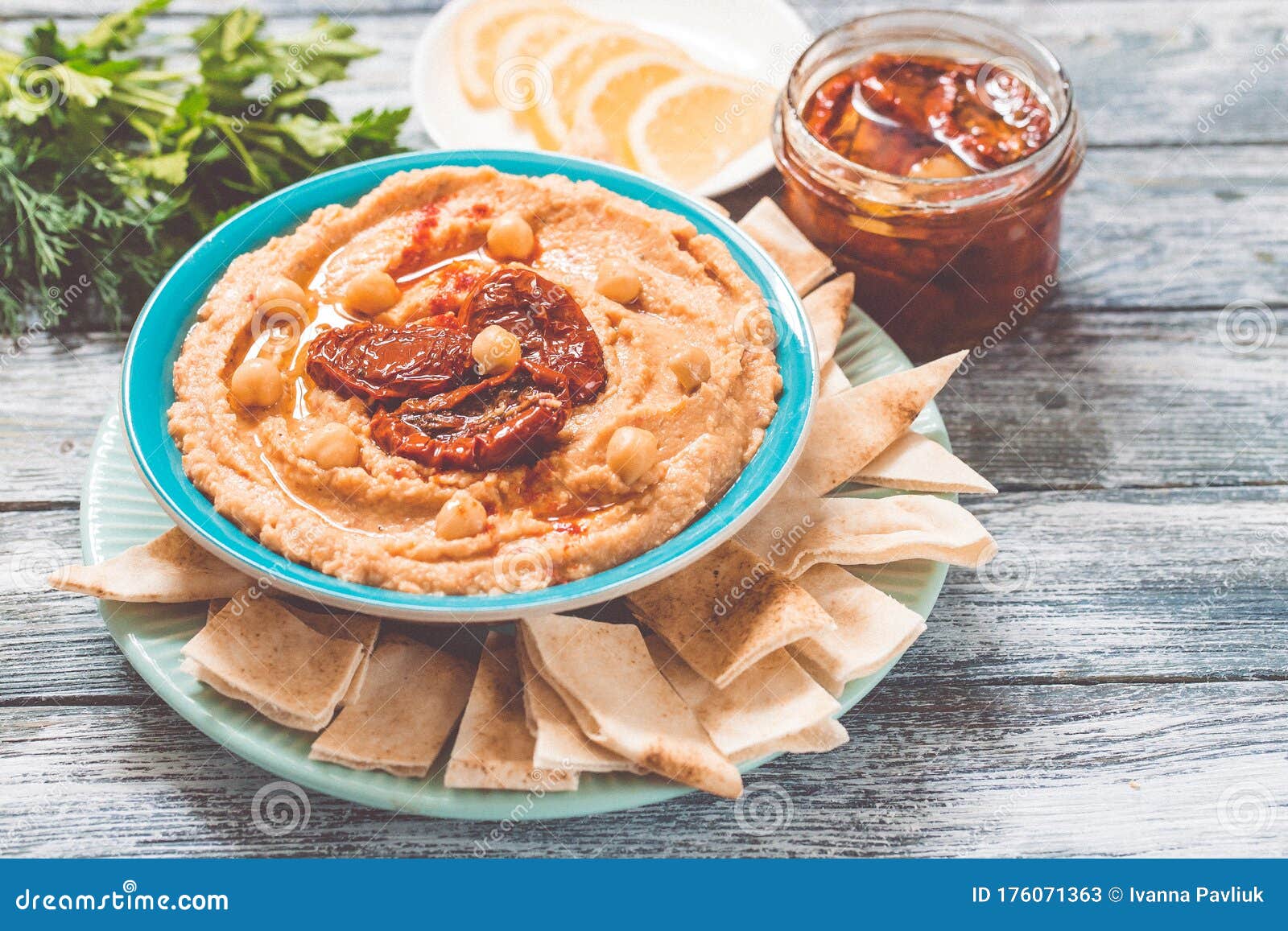 a bowl of creamy homemade hummus with with sun-dried tomatoes, olive oil and pita chips. traditional vegan healthy meal