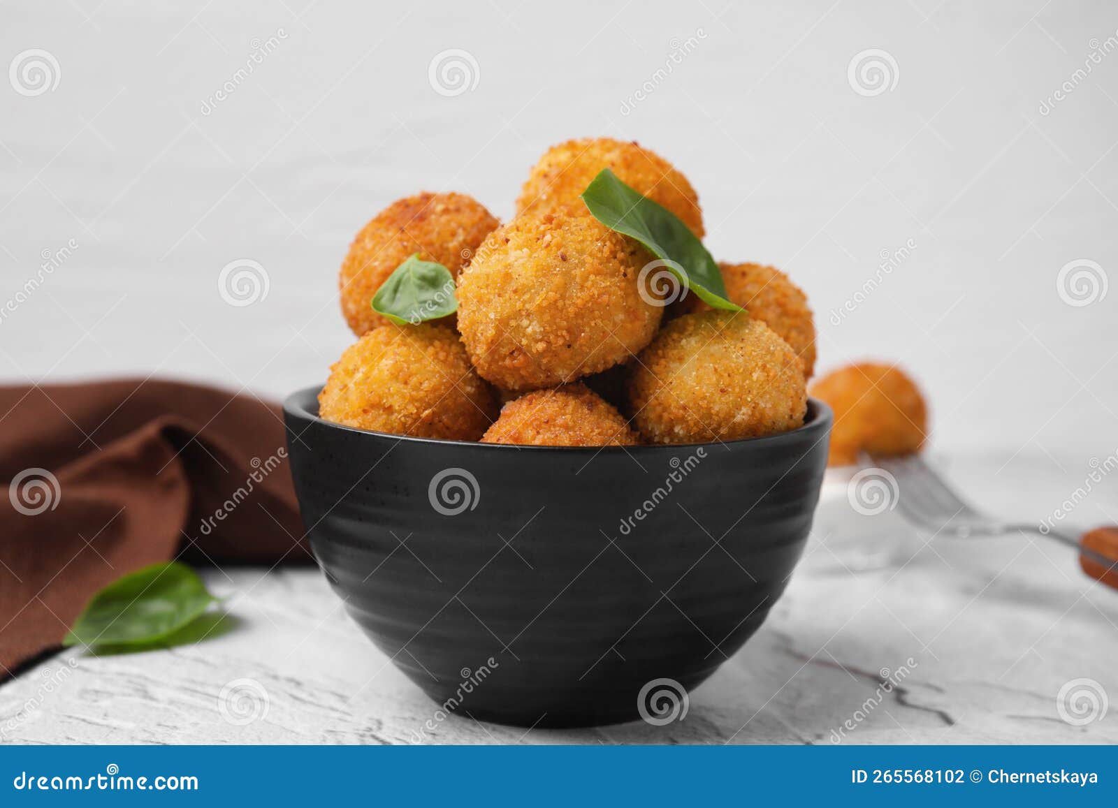 Bowl of Delicious Fried Tofu Balls with Basil on Textured Table Stock