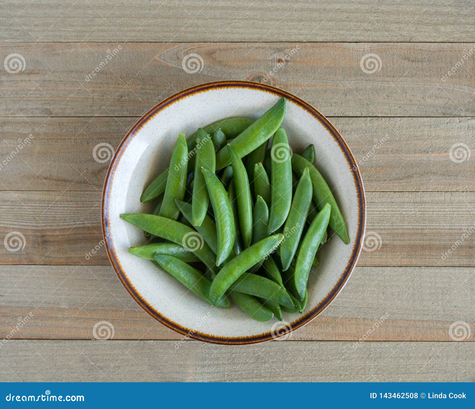a bowl of sugar snap peas on a wood background