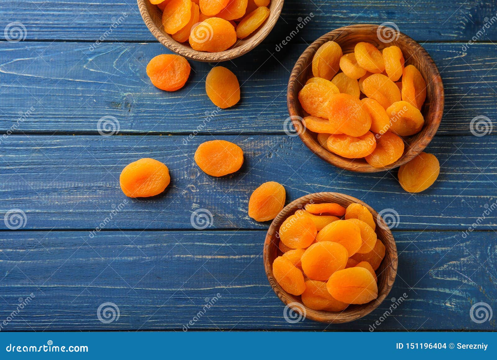 bowls with dried apricots on wooden table