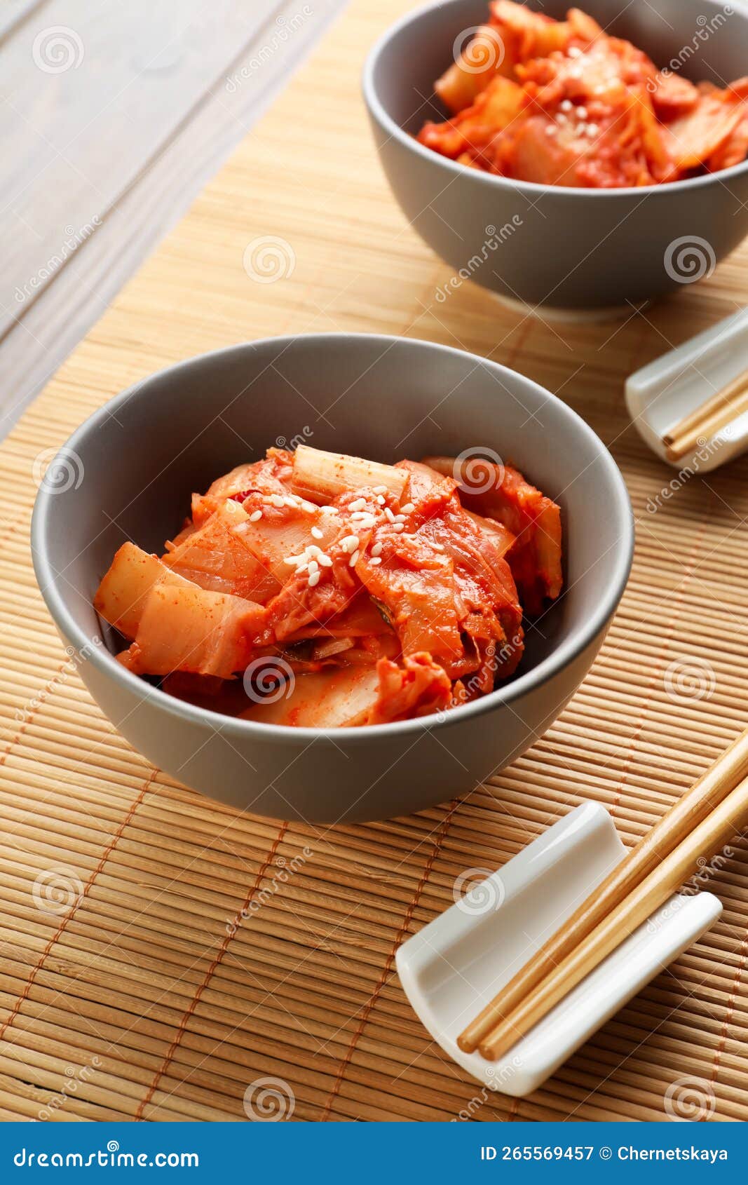 Bowls of Spicy Cabbage Kimchi and Chopsticks on Bamboo Mat Stock Image