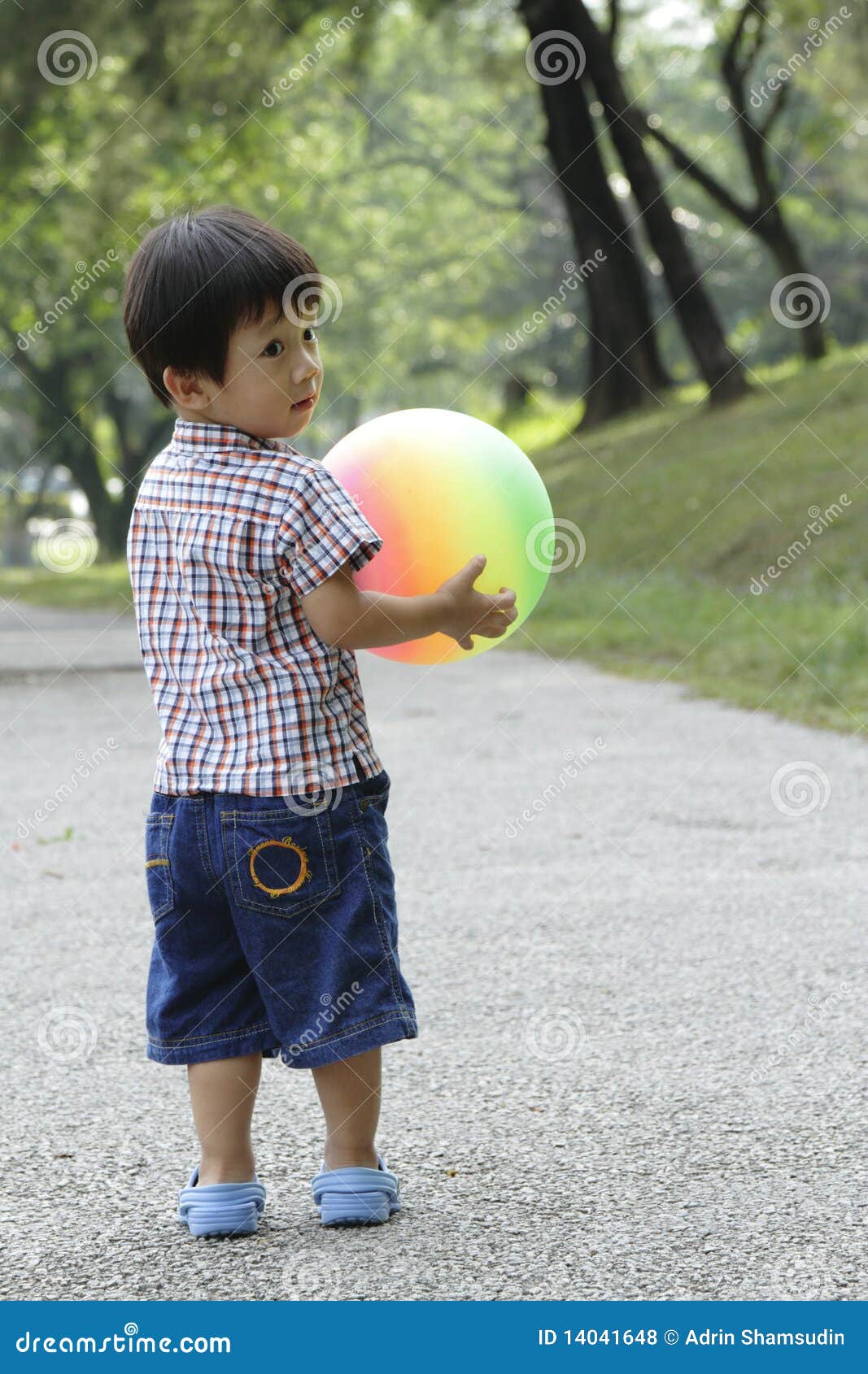 Boy with ball. An Asian boy playing with a colorful ball at a public park