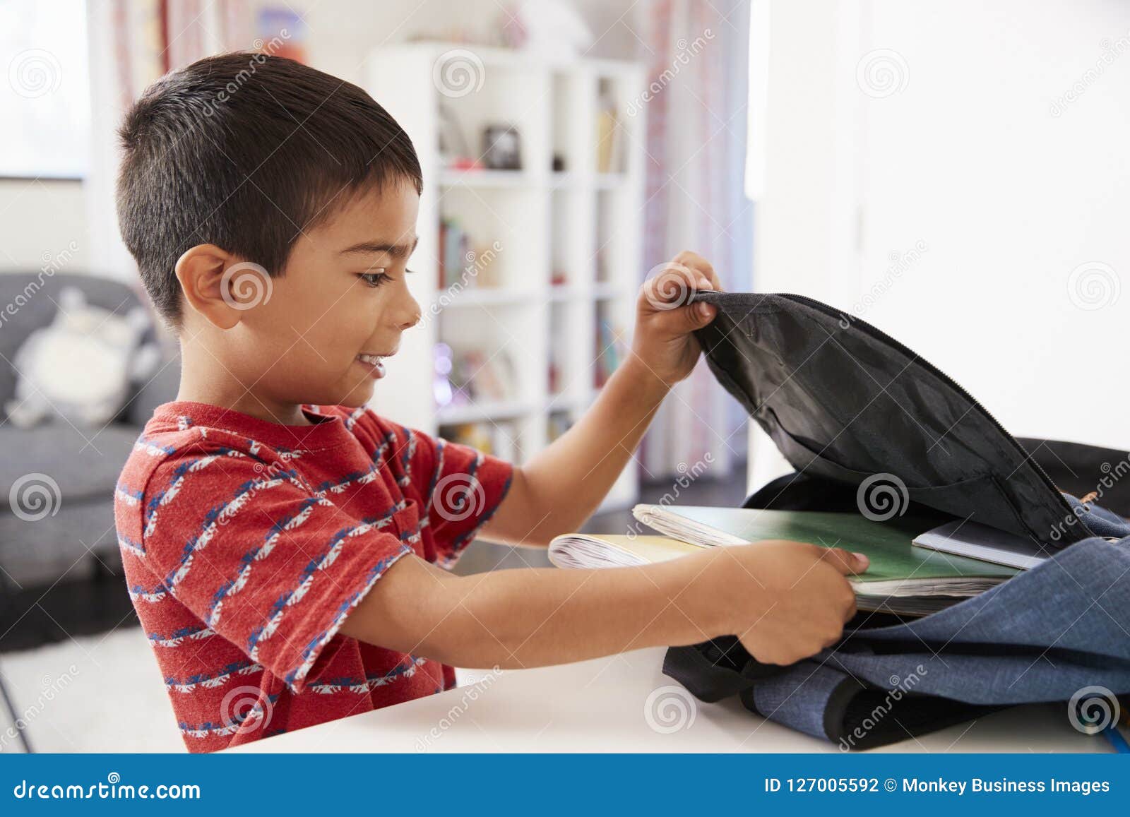 boy in bedroom packing bag ready for school