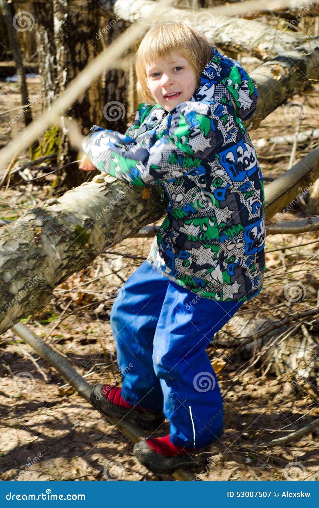 A boy climbs on a tree in the spring forest