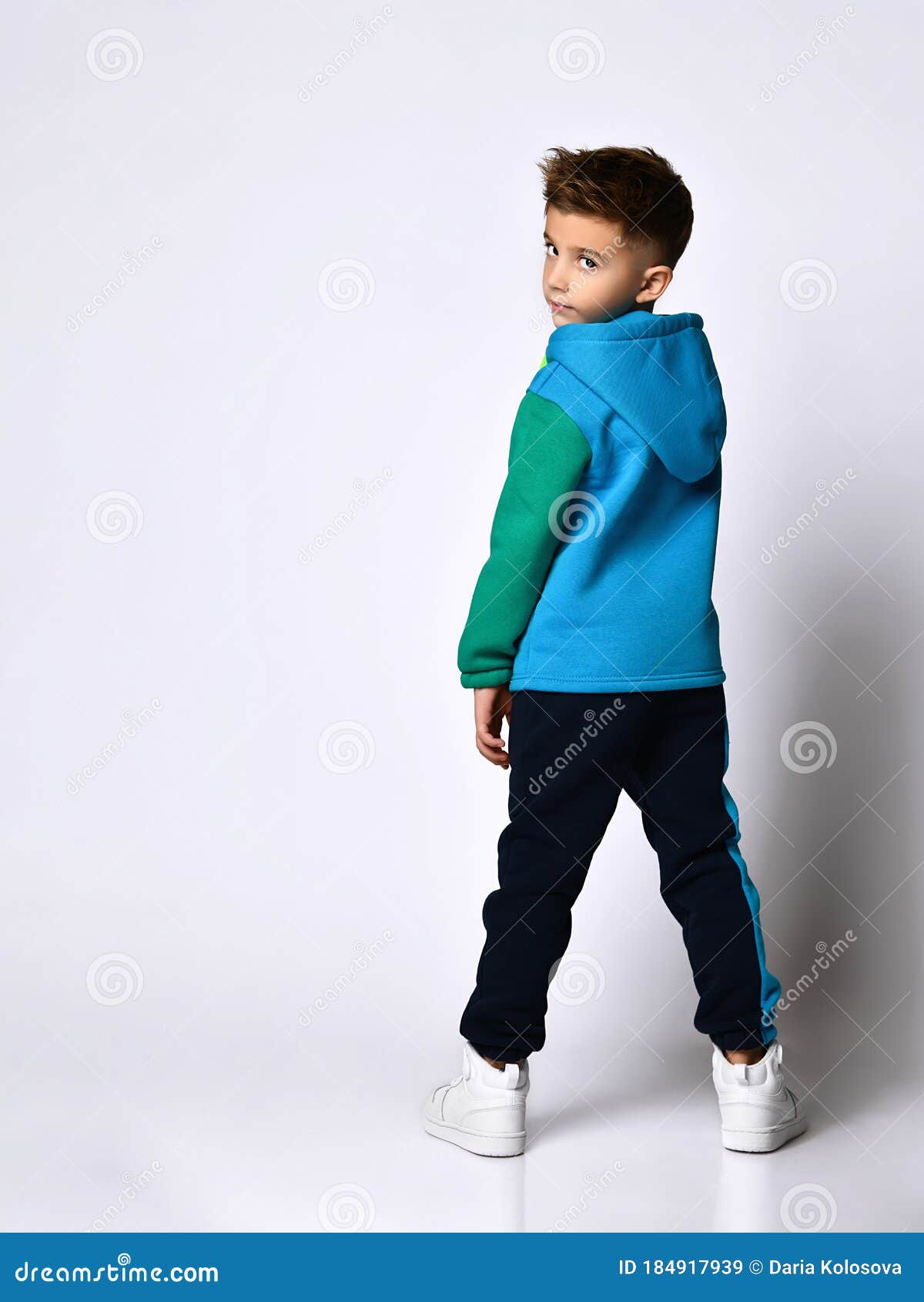 boy colorful sport suit sneakers looking back posing standing to camera isolated white studio little background childhood 184917939