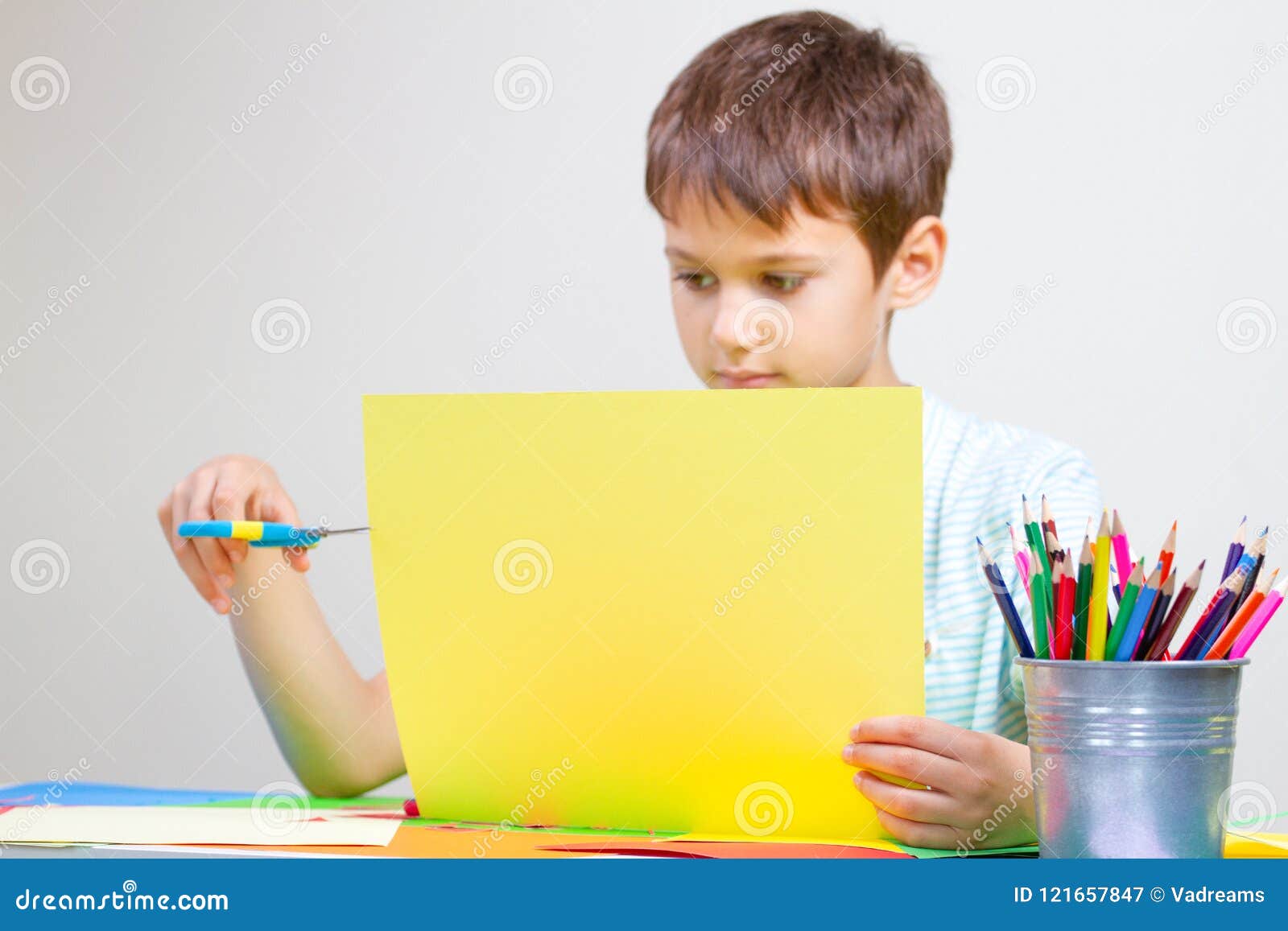 Boy Cutting Colored Paper with Scissors at the Table Stock Image