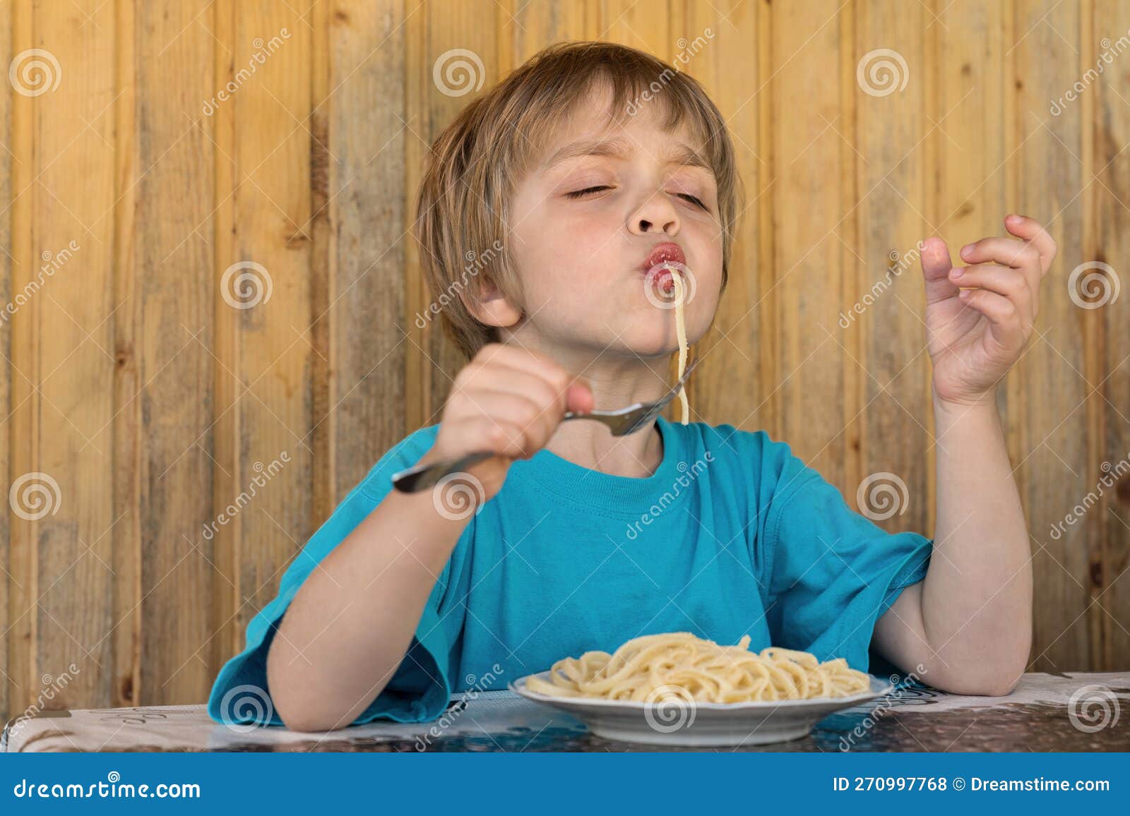 The Boy is Eating Spaghetti. he Narrowed His Eyes with Pleasure