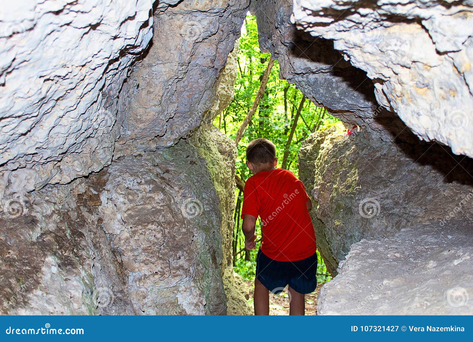 the boy exits the cave in the rock, the rear view.