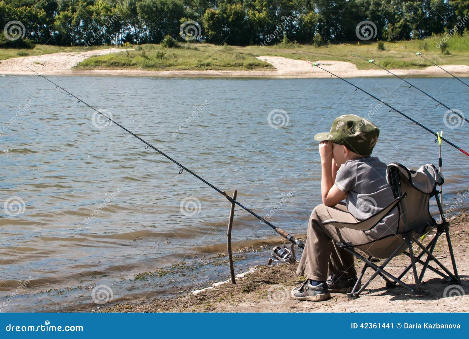 Boy with Fishing Rod Sitting on the Shore of the Pond. Stock Image