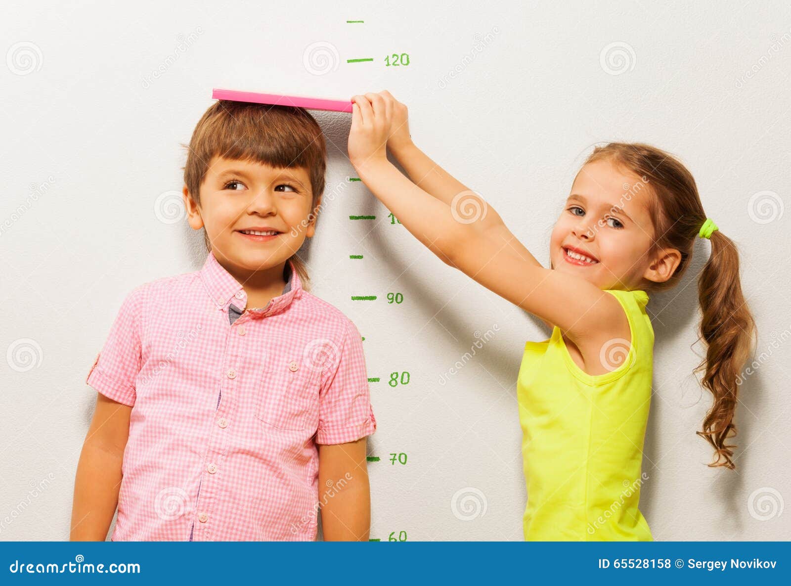 boy and girl measure height by wall scale at home
