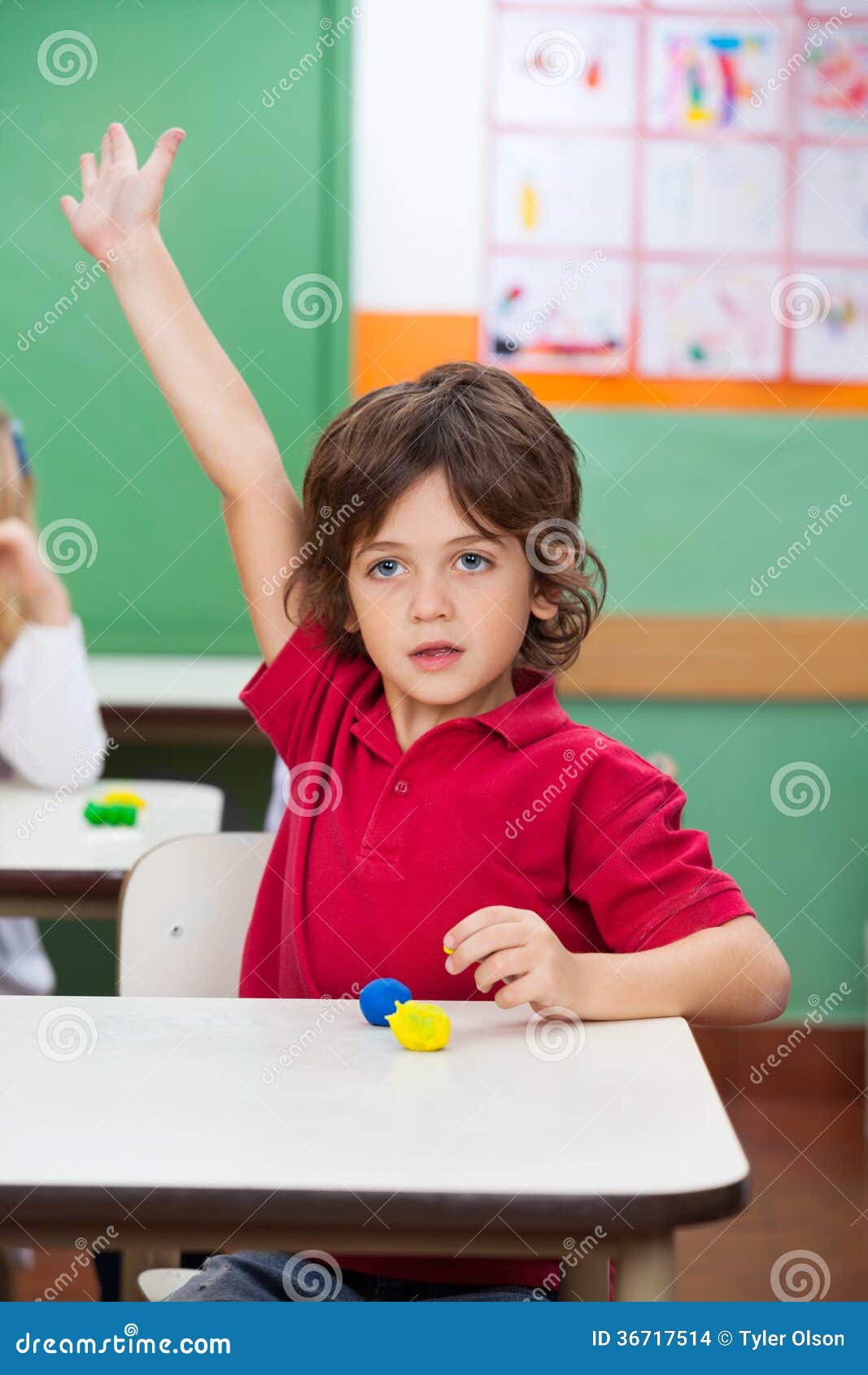 Boy with Hand Raised Sitting at Desk Stock Photo Image of childhood