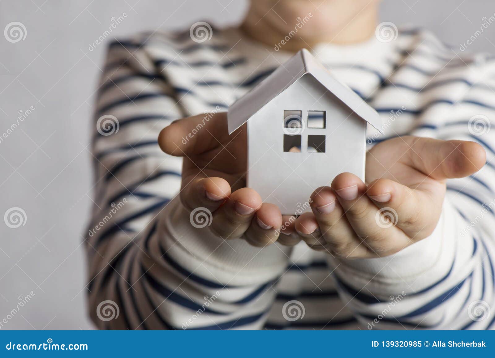 the boy holds in his hands the little white house. the concept of real estate, purchase, adoption.