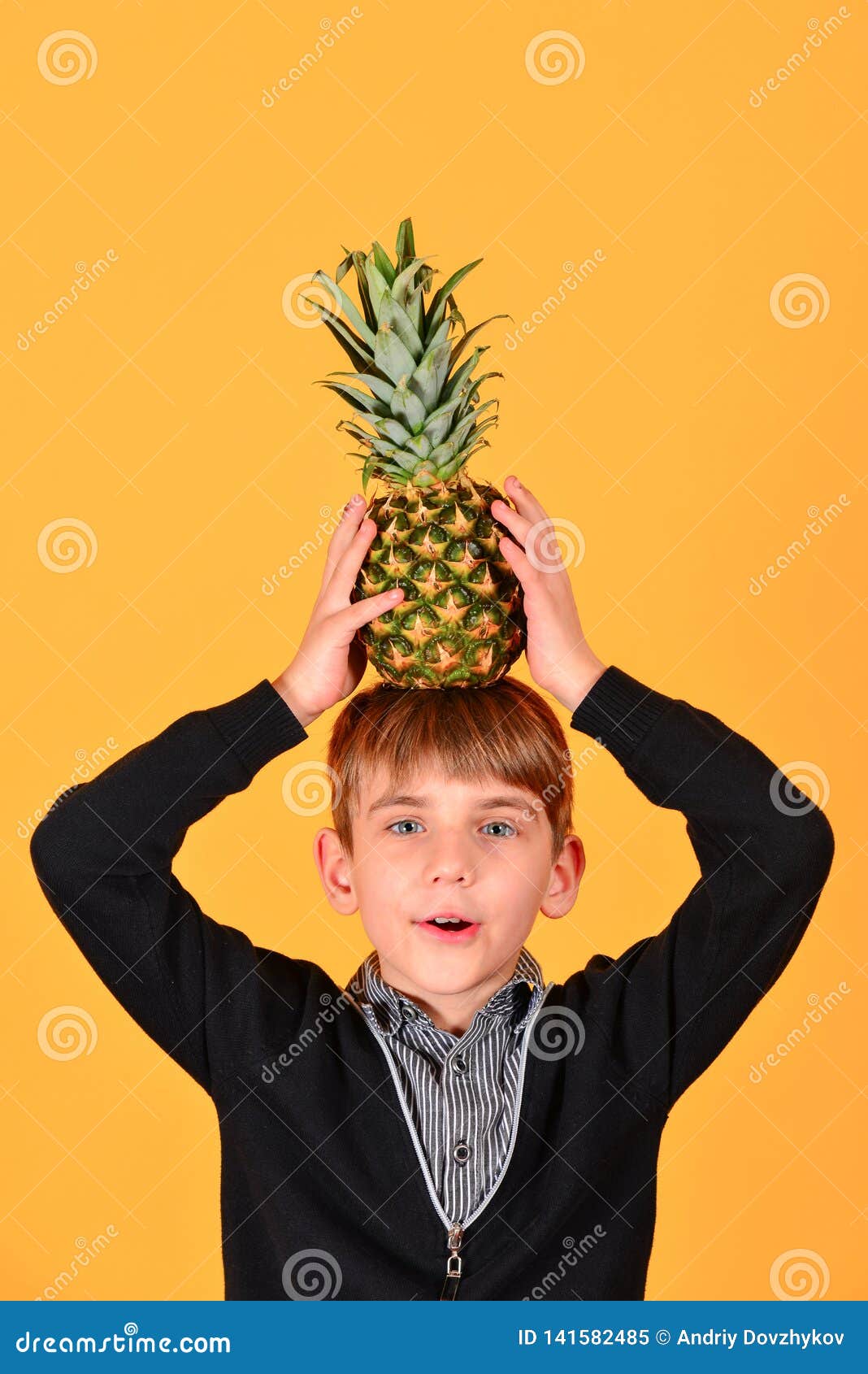 The Boy Holds a Pineapple on His Head, on a Yellow Background Stock