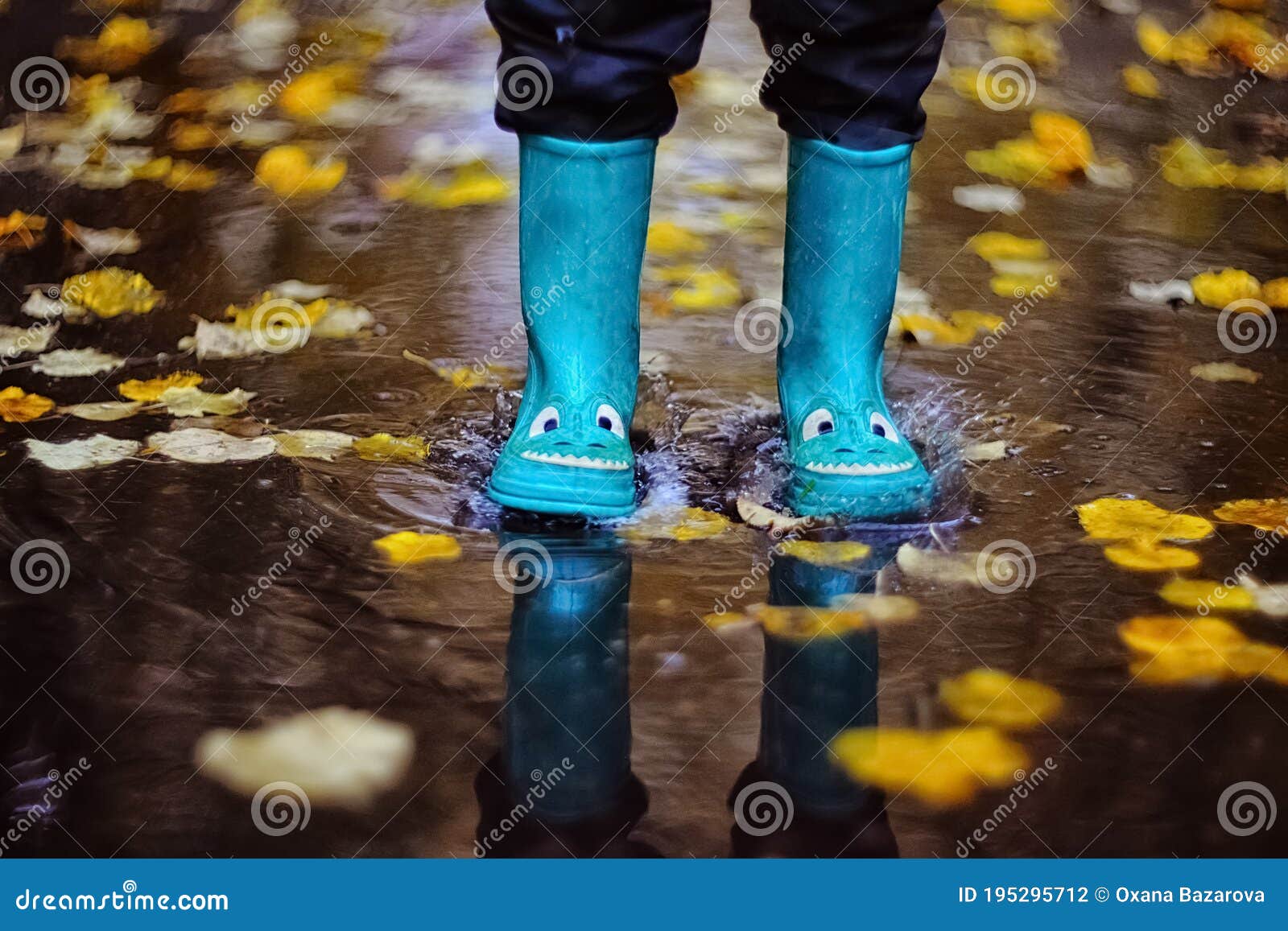 Boy Jumping in Rubber Boots through Puddles in Autumn Stock Photo