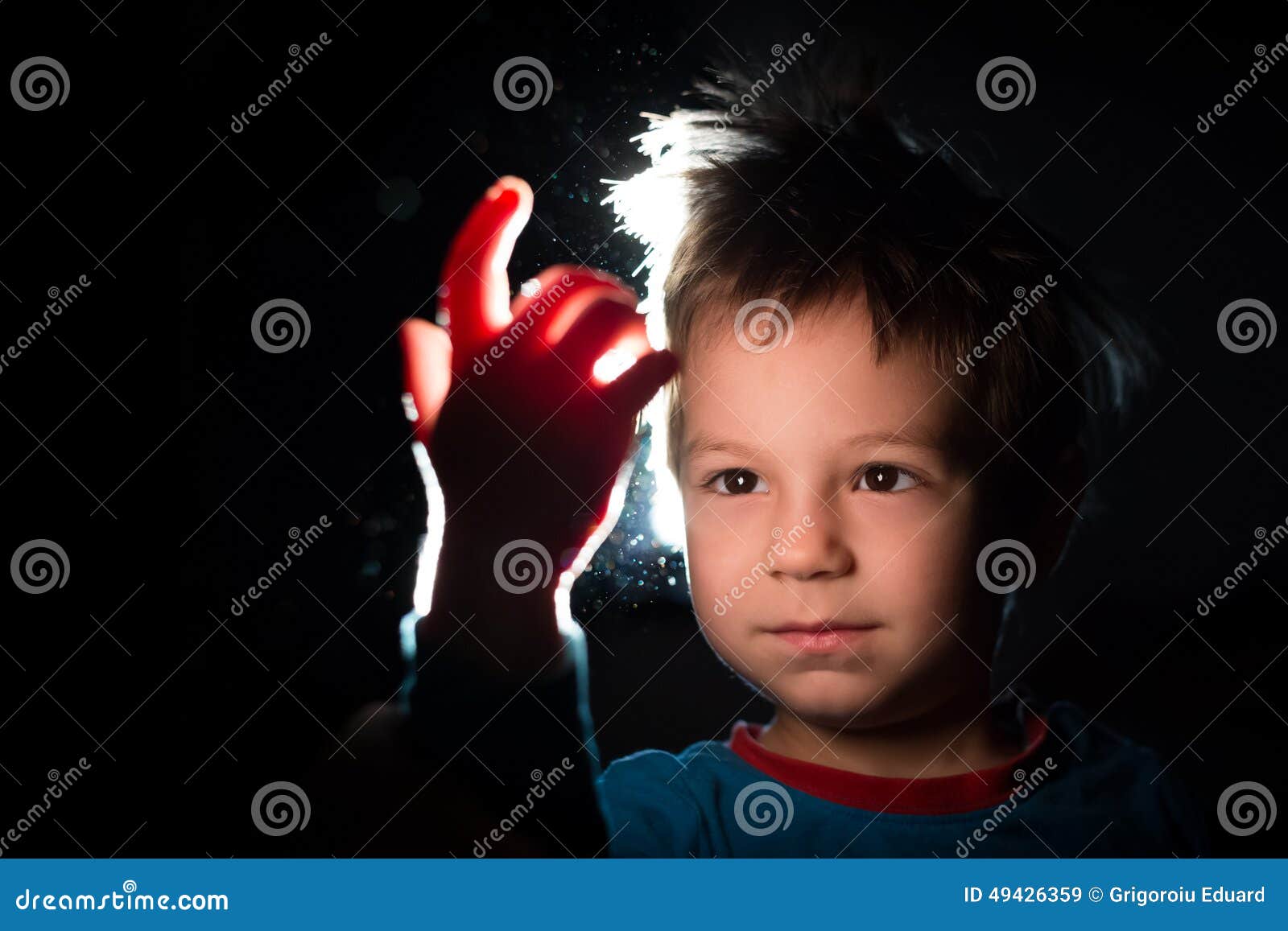 boy looking with great curiosity at his hand in a ray of light