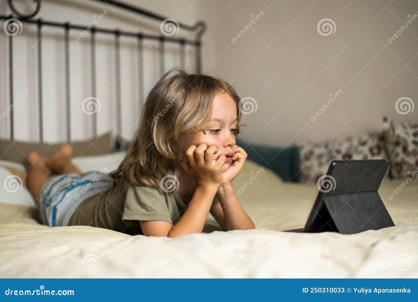 Boy Lying on the Bed Using Digital Tablet Computer Playing Games or