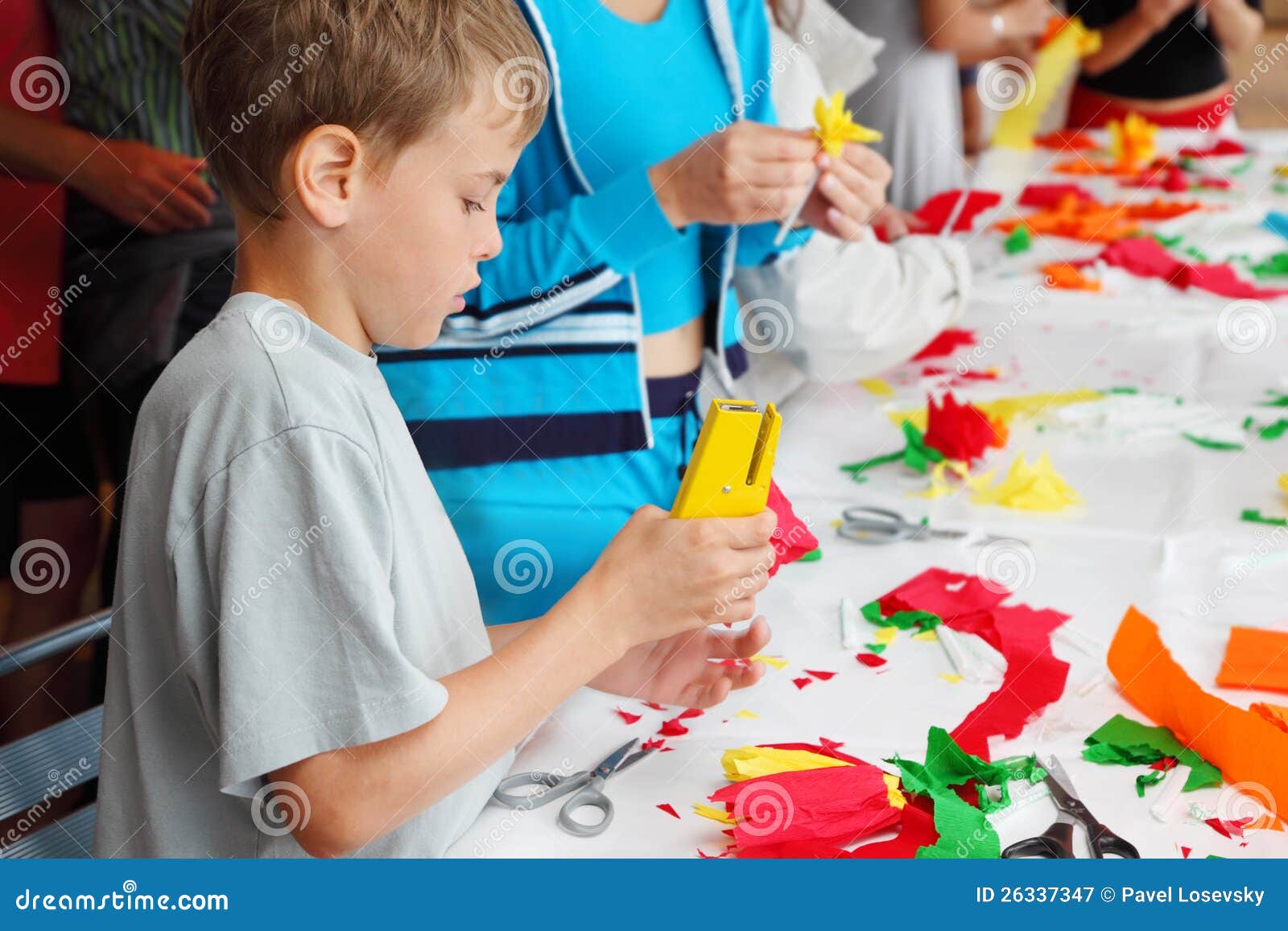 boy makes flower of tissue paper by stapler