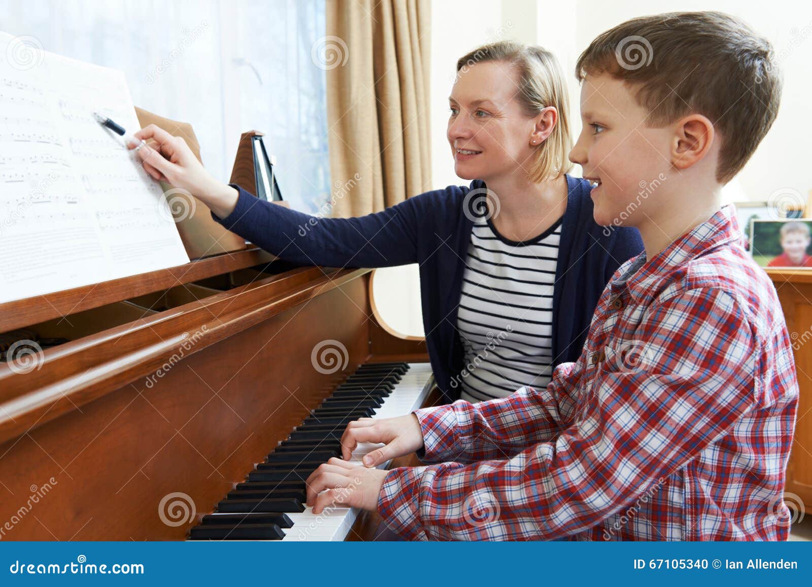 boy with music teacher having lesson at piano