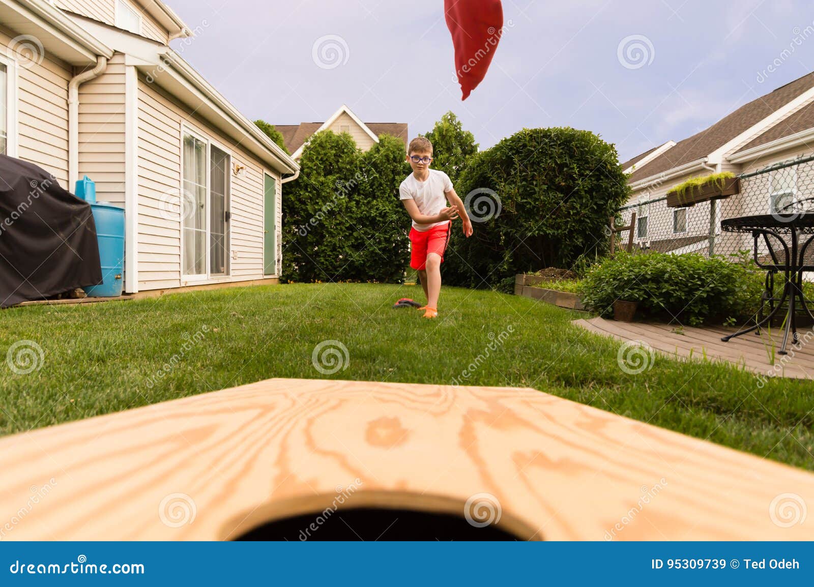 boy playing bean bag toss in the backyard!