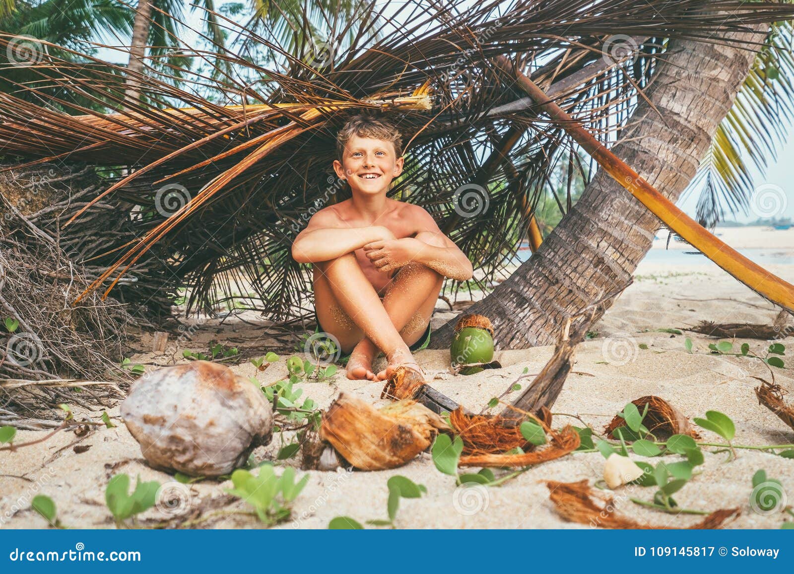 boy plays in robinzon on tropical beach in hut of branches