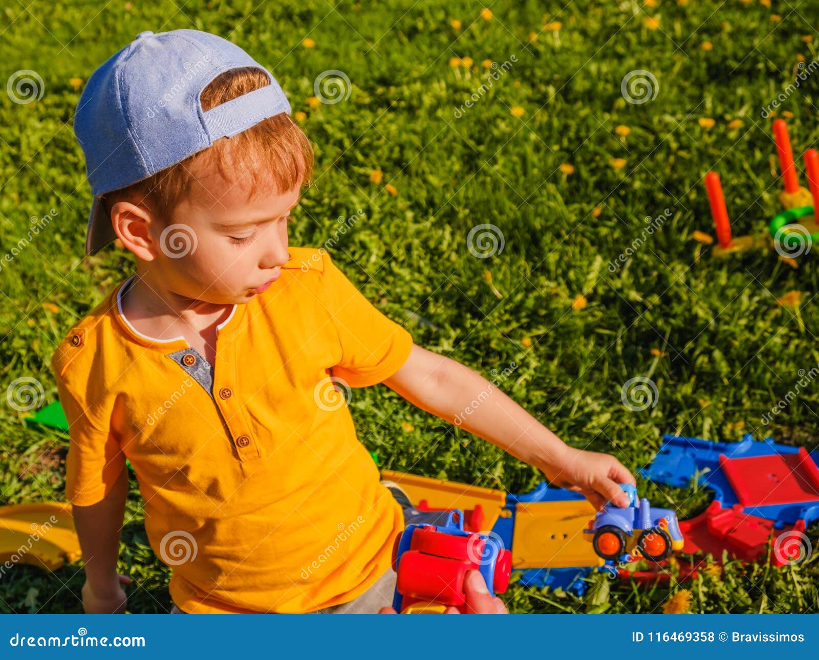 Boy Plays with a Toy Car on the Green Lawn. Stock Photo Image of