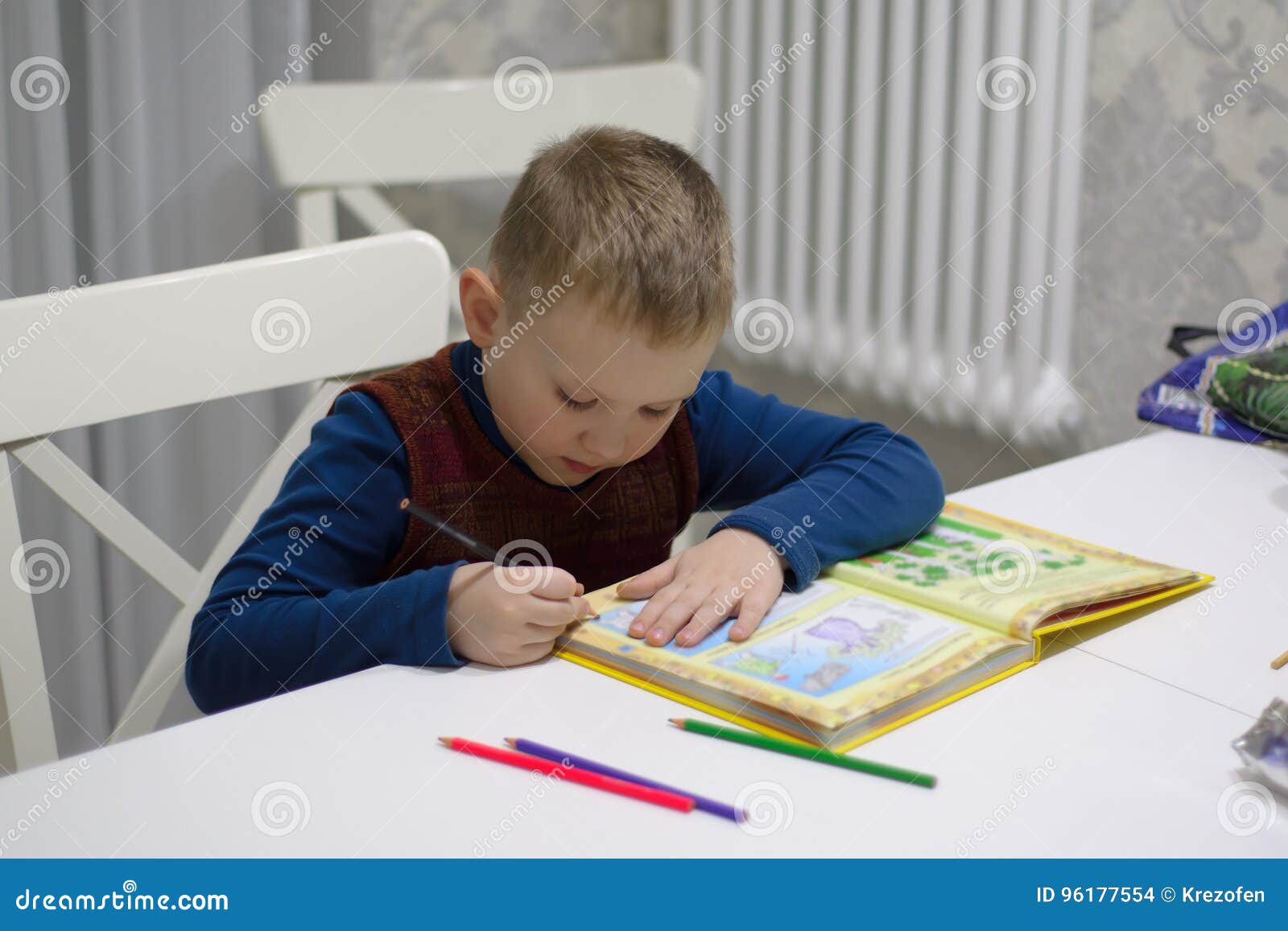 Boy reading a book. Boy sitting at a table and reading a book