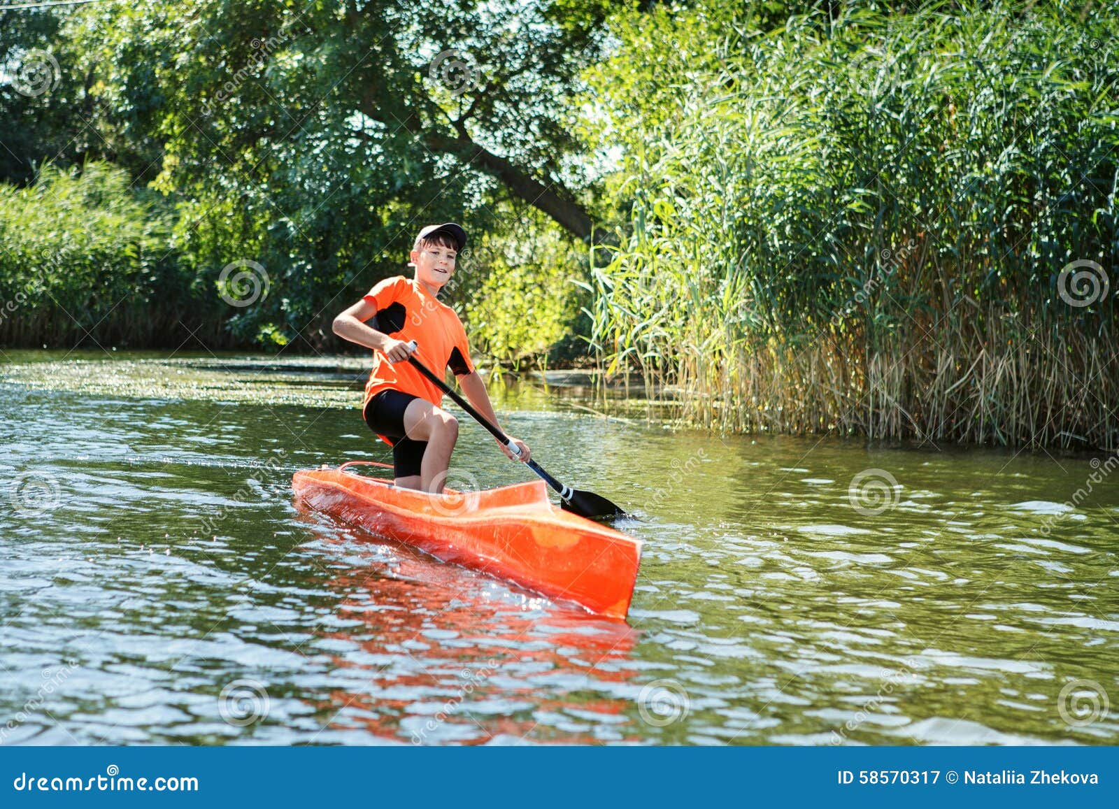 The Boy Rowing In A Canoe On The River. Stock Photo 