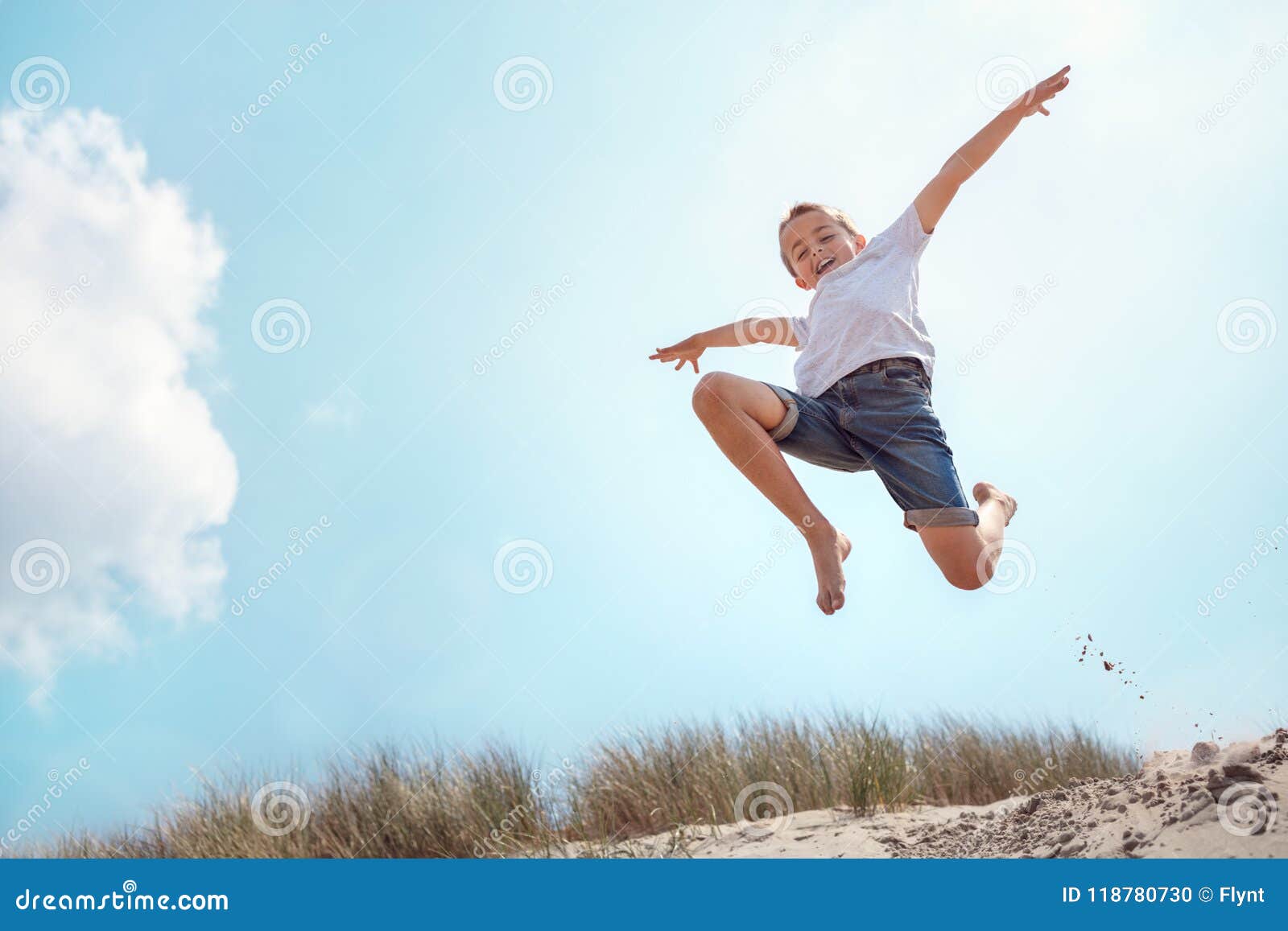 Boy Running and Jumping Over Sand Dune on Beach Vacation Stock Photo