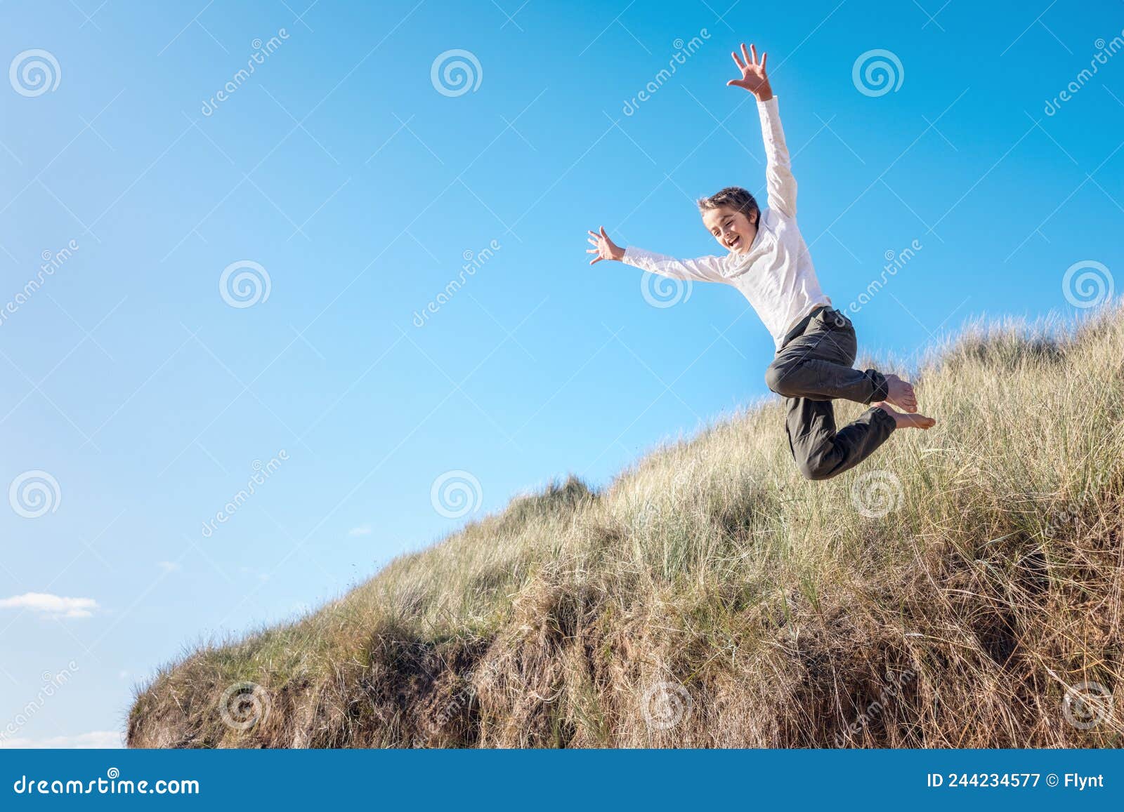 Boy Running and Jumping Over Sand Dunes on Beach Vacation Background