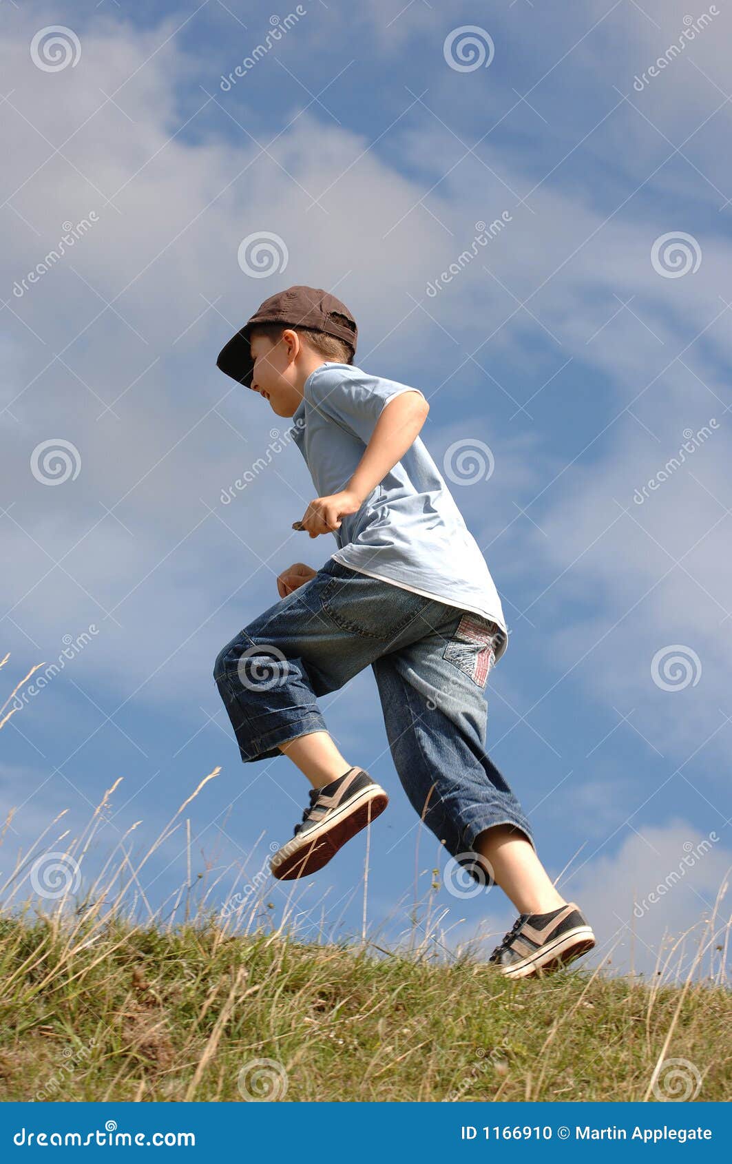 a boy running up a grass hill