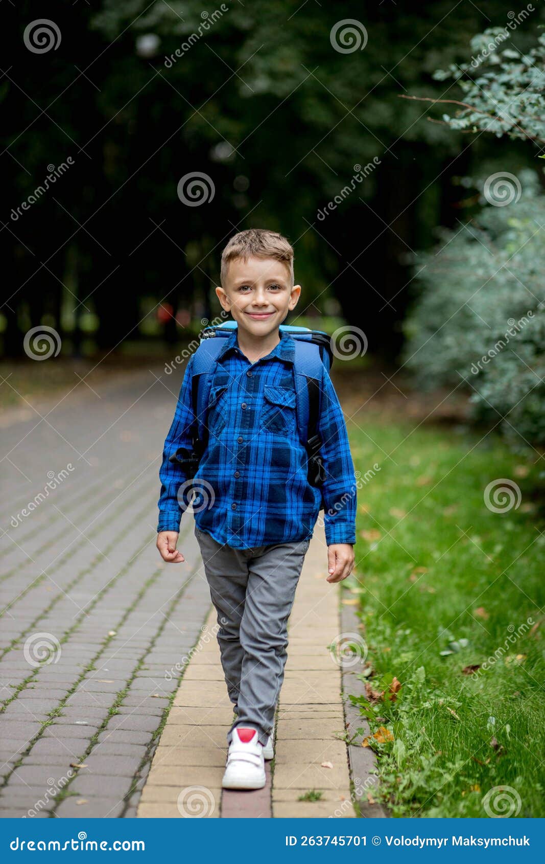 Boy of School Age with a Blue Backpack Goes To School in the Park Stock