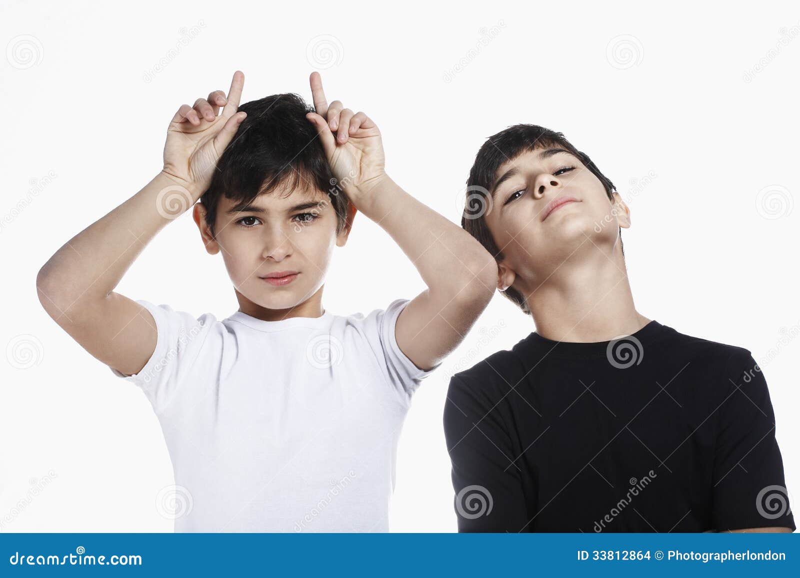 Boy Showing Rude Gesture While Standing With Brother Stock