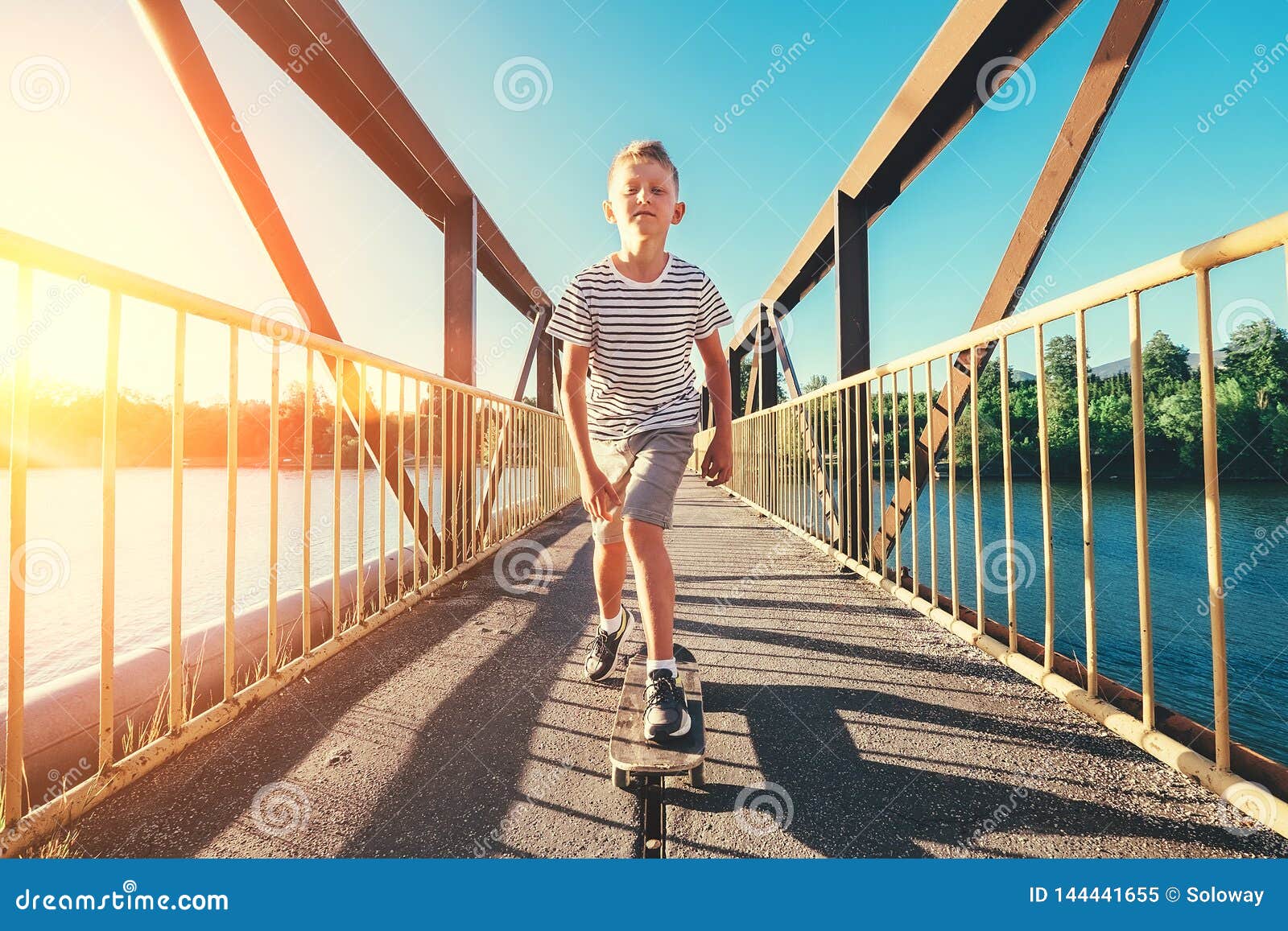 Boy Skates on Skate Board on the Bridge Over Tthe River Stock Image
