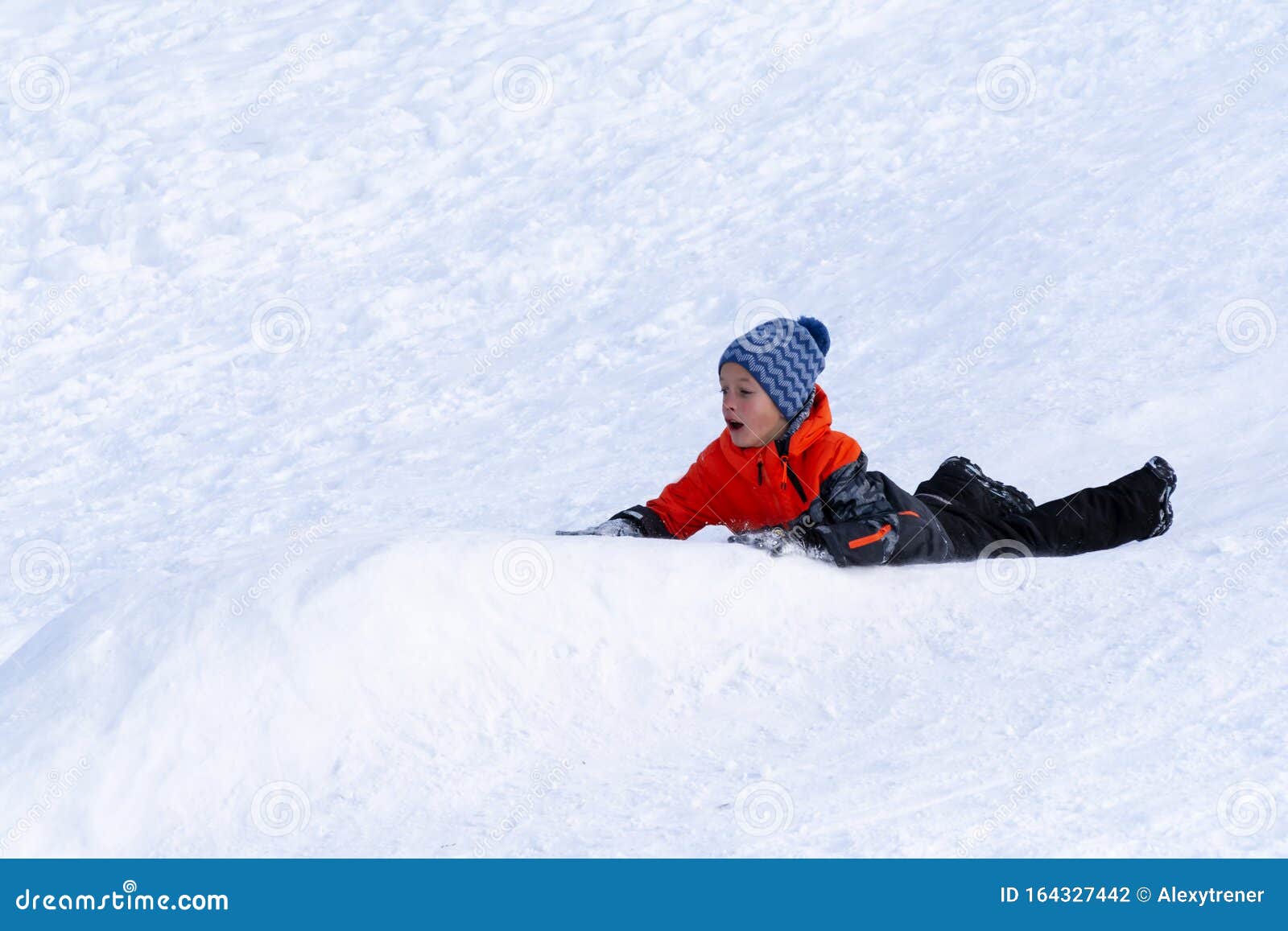 Boy Sledding Down the Hills without Sledge on a Winter Day Stock Photo