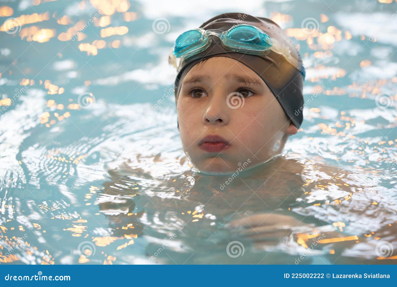 Boy in a Swimming Cap and Swimming Goggles in the Pool Stock Photo