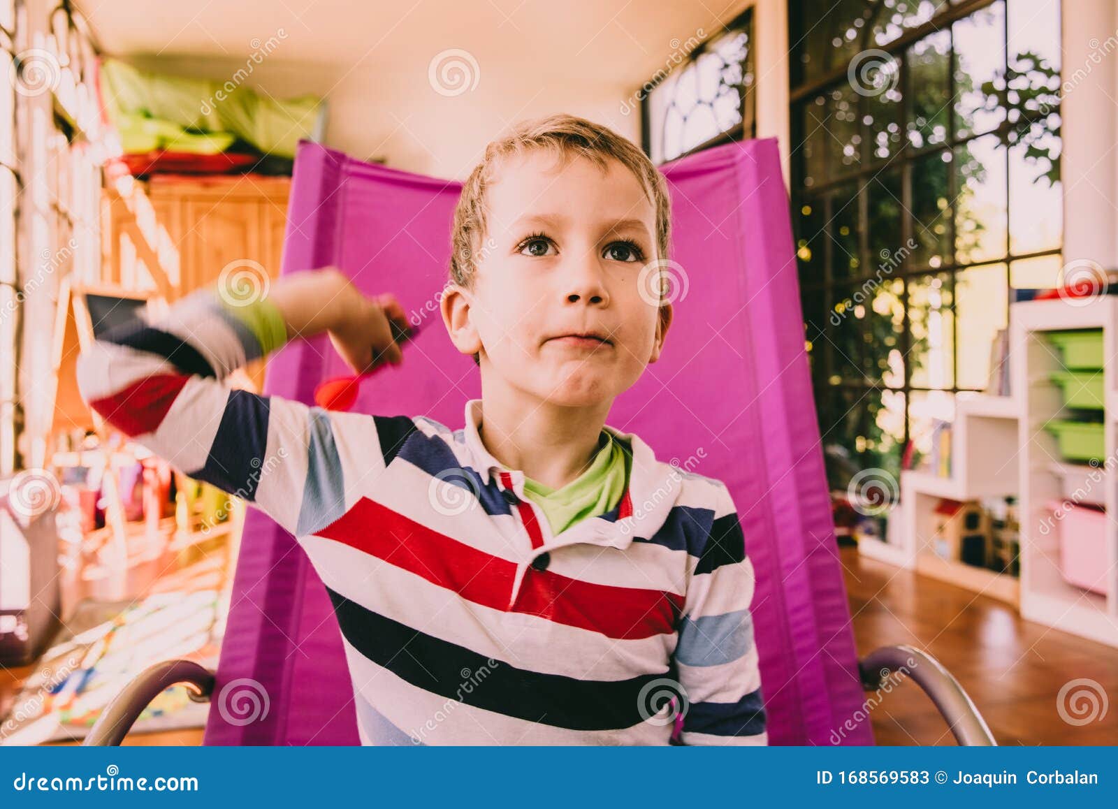 Boy Throwing Darts Sitting in a Pink Chair Stock Image Image of