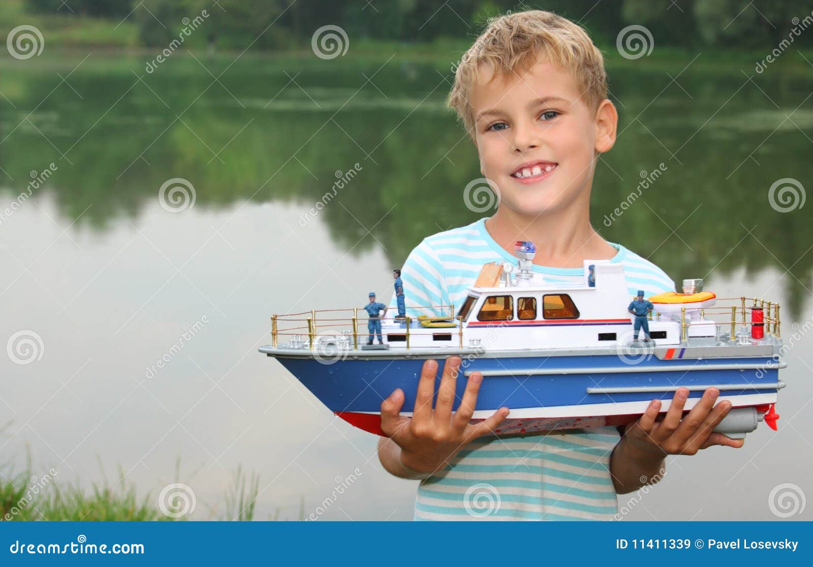 boy with toy ship in hands ashore