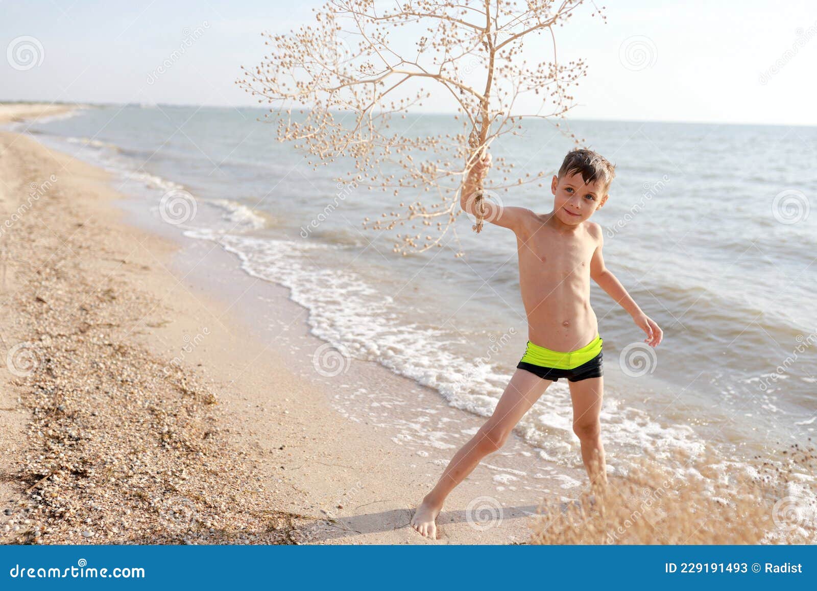 boy with tumbleweed plant on beach of azov sea