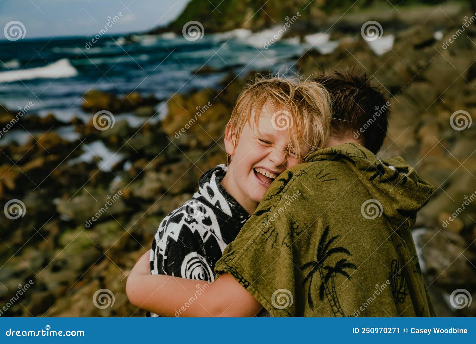 boys wearing hooded towels after swimming mucking around on rocks at the tanks tourist attraction at forster, nsw australia