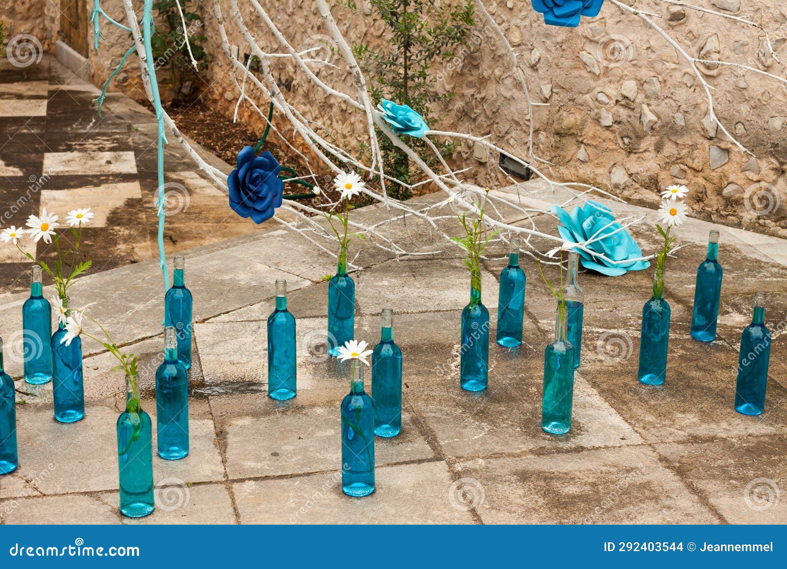 branch with blue roses and some blue bottles with daisies on the floor on 